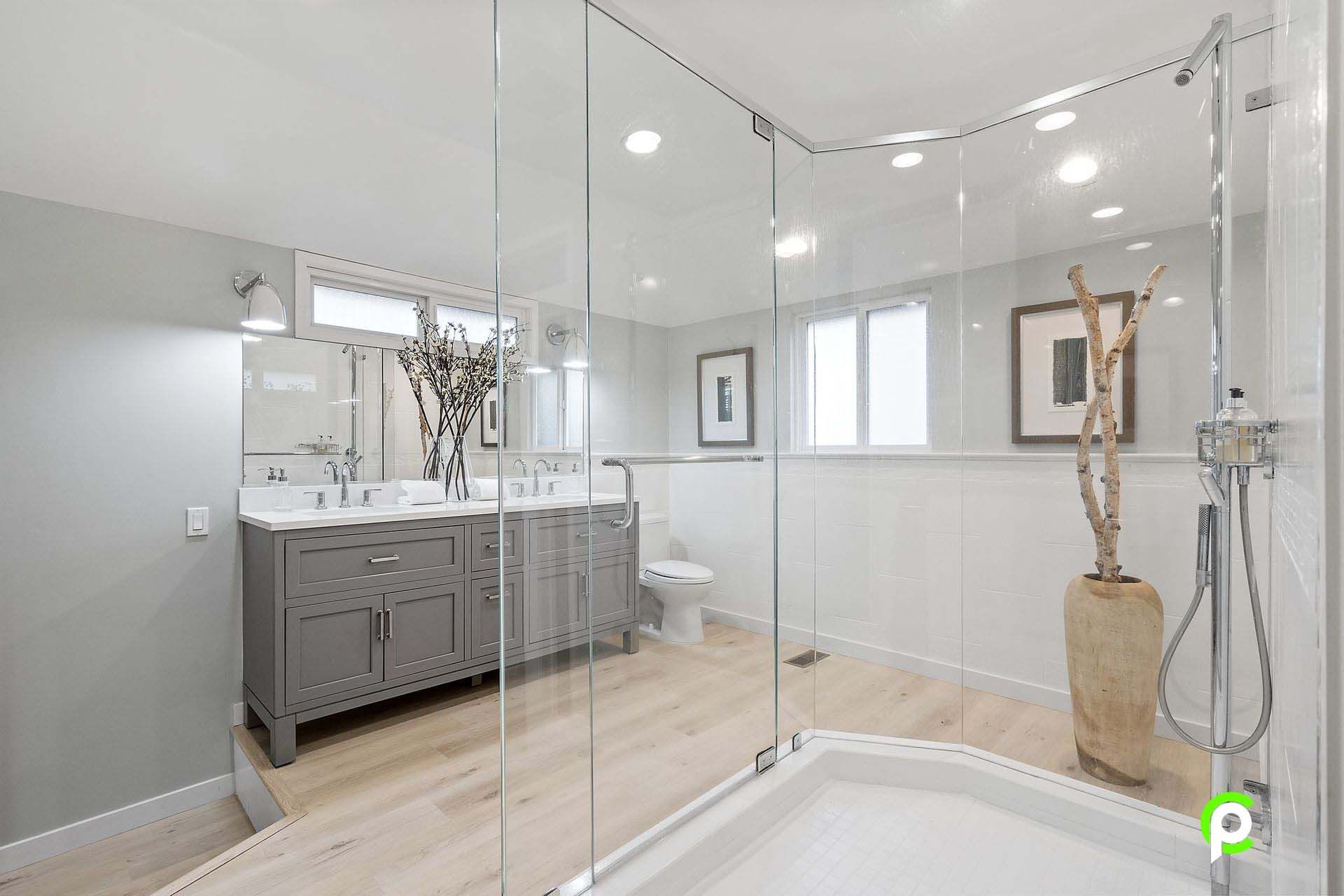 A bathroom with two sinks , a toilet , and a walk in shower.