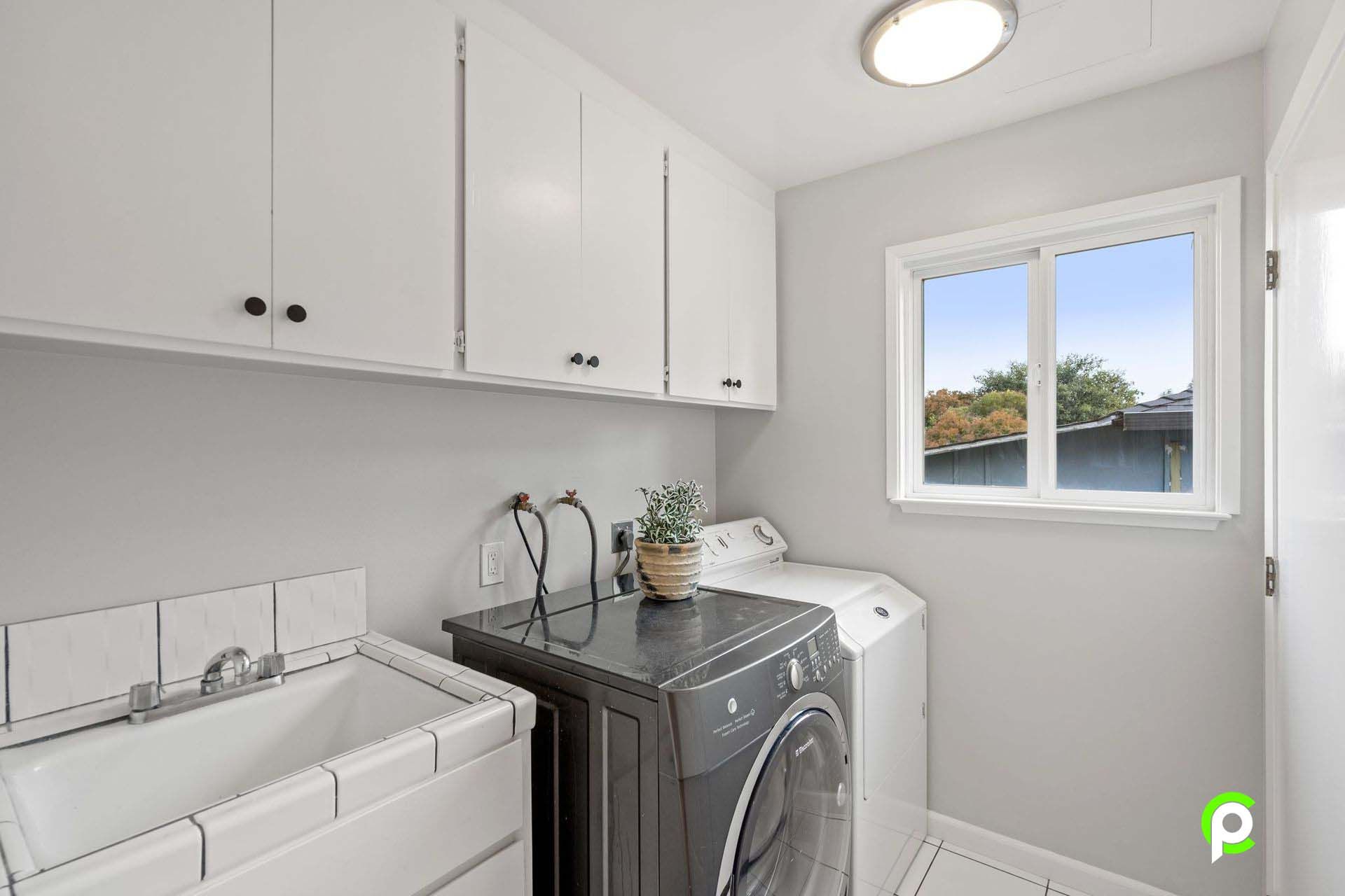 A laundry room with a washer and dryer , sink and window.