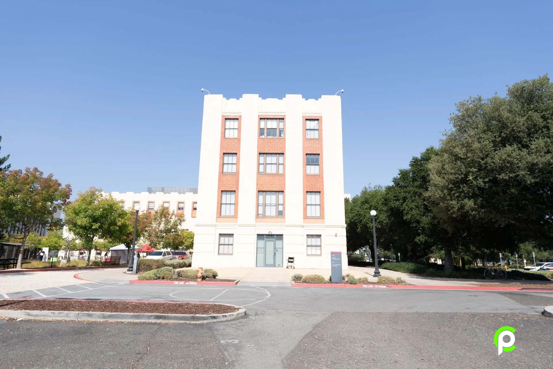 A large white building with a lot of windows and trees in front of it