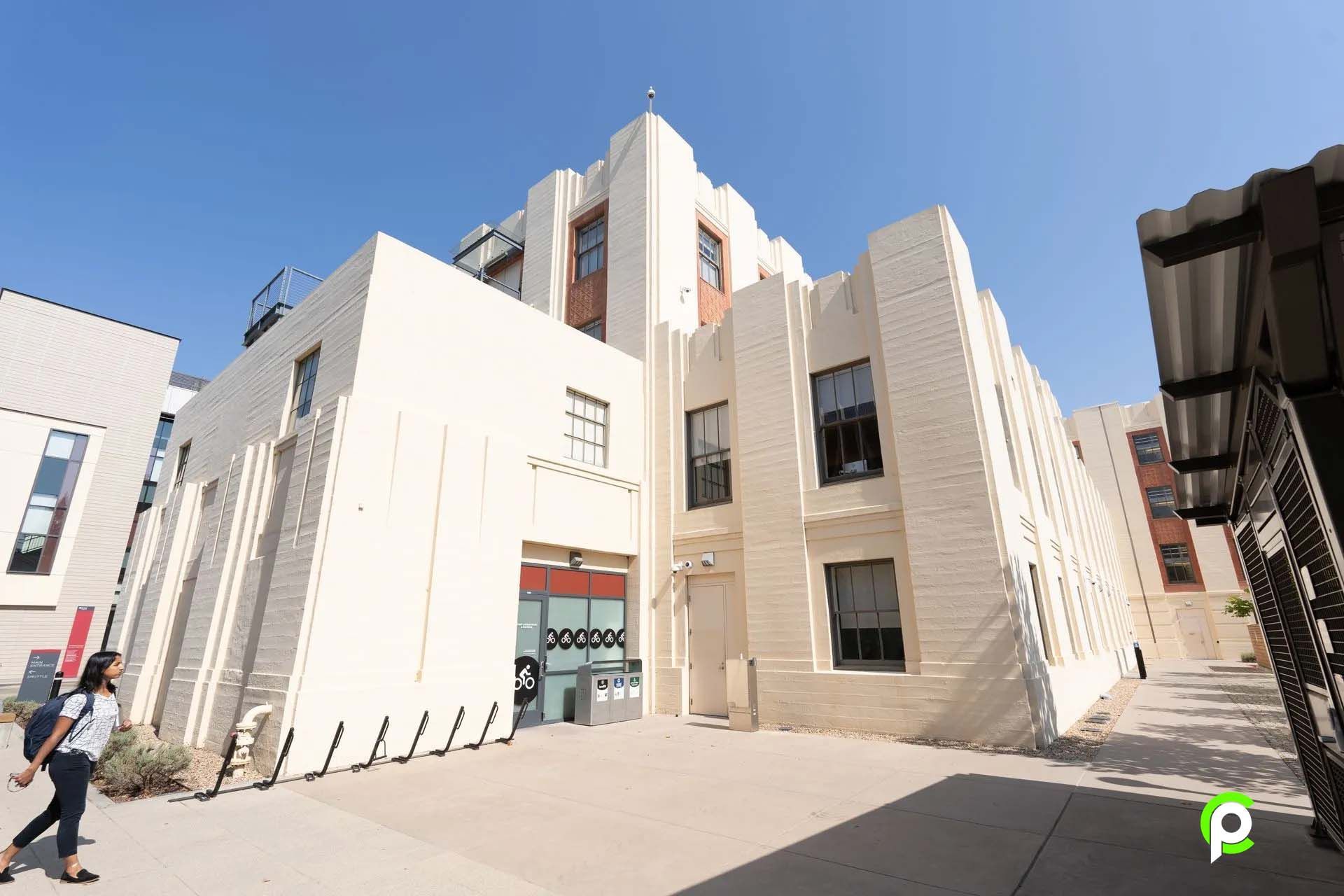 A large white building with a lot of windows and people walking in front of it.