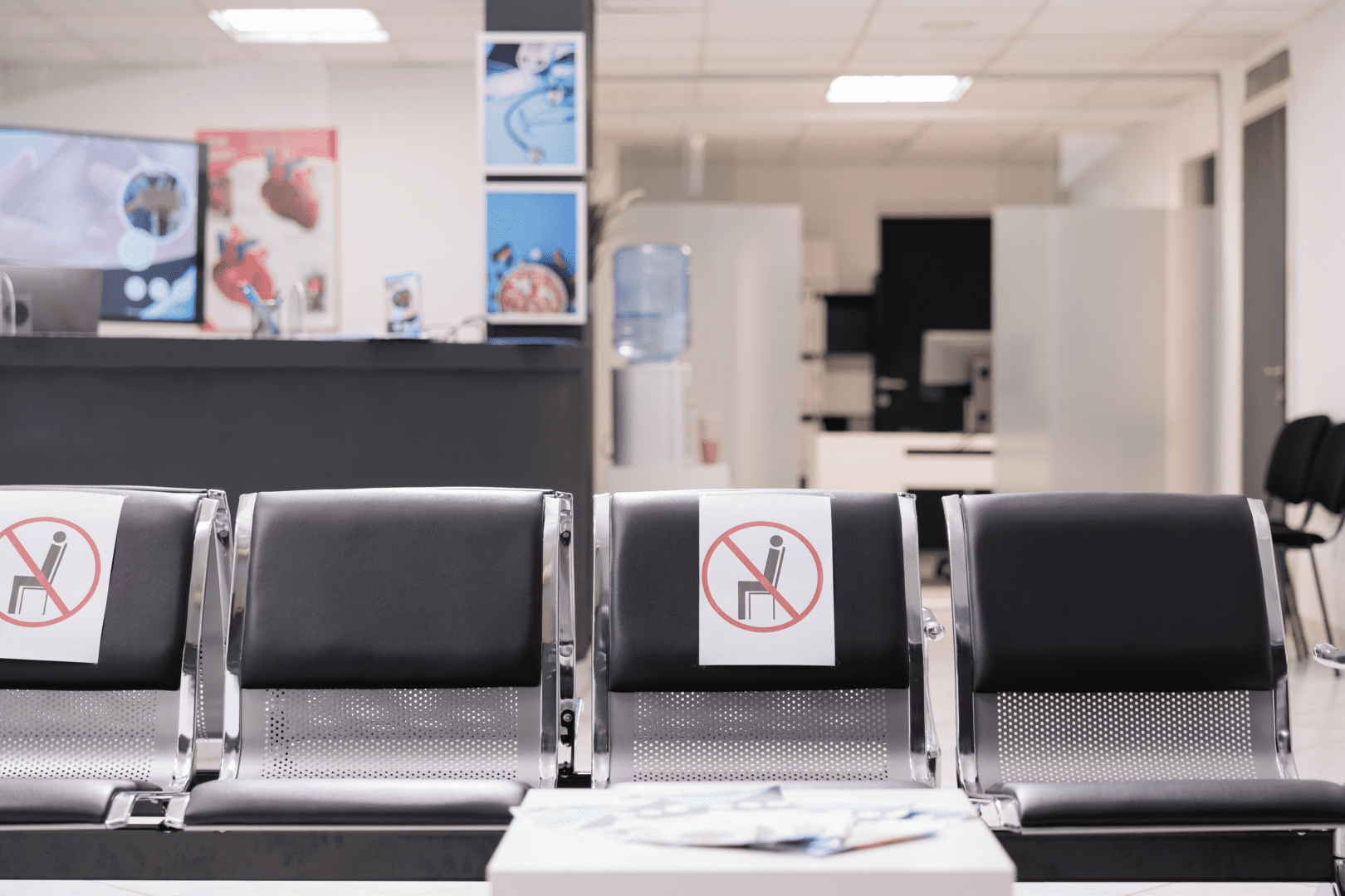 A row of chairs in a hospital waiting room with signs on them.