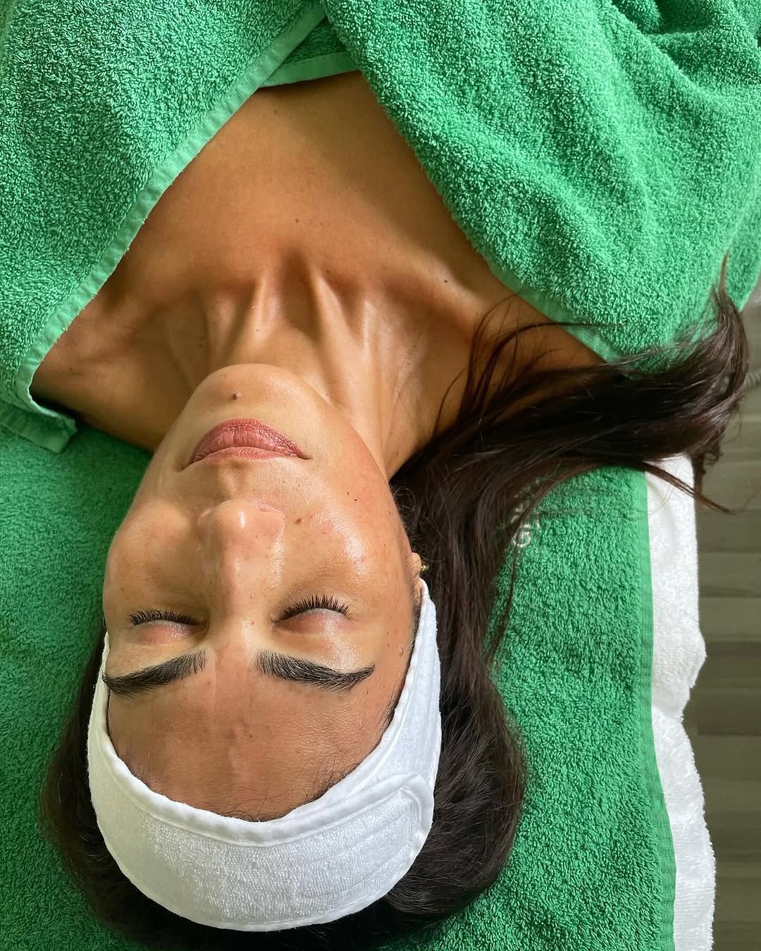 Eine Frau liegt auf dem Rücken mit einem grünen Handtuch um den Kopf