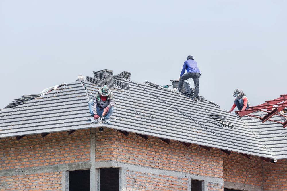 Construction Workers Installing Gray Roof Tiles on A New House — Newcastle Roofing Wizards In Maitland, NSW