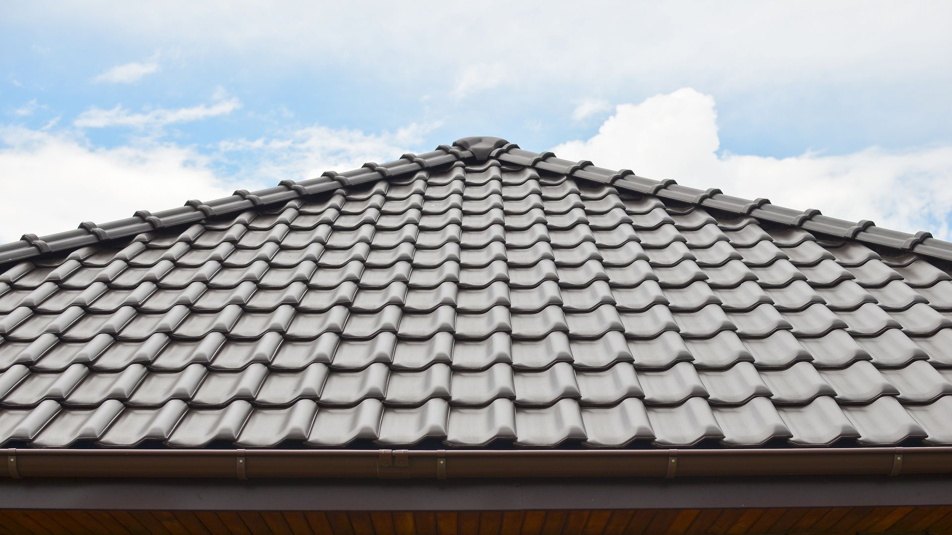 Gray Tiled Roof Against a Cloudy Blue Sky — Newcastle Roofing Wizards In Tingira Heights, NSW