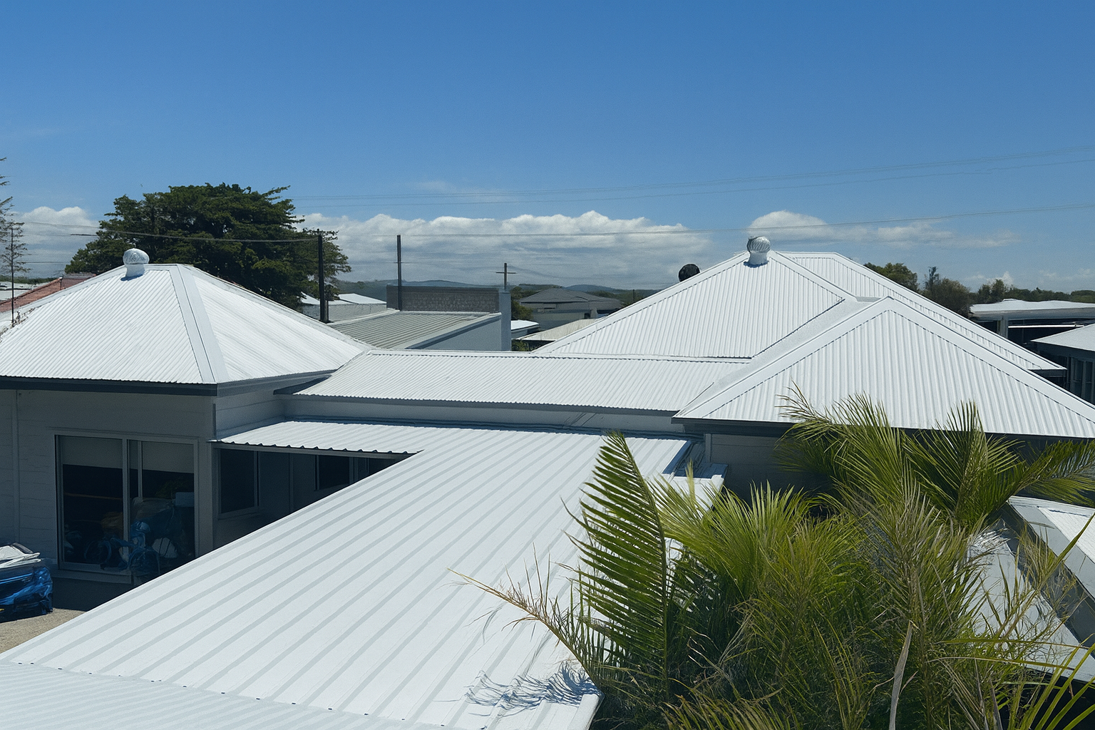 Three Construction Workers Installing a Dark Blue Metal Roof — Newcastle Roofing Wizards In Tingira Heights, NSW