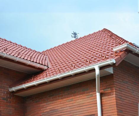 A brick house with a red tiled roof and gutters