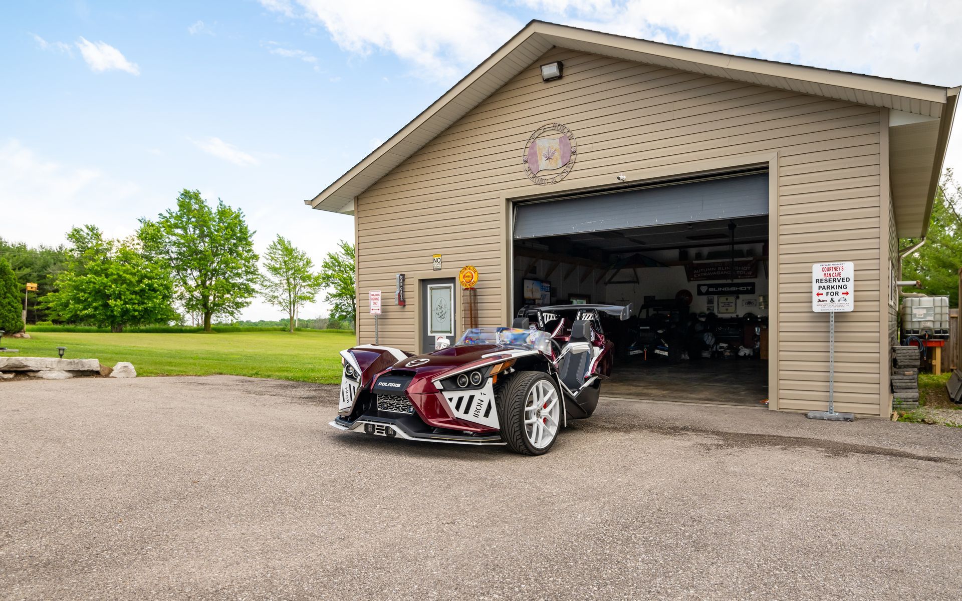 A red slingshot is parked in front of a garage.