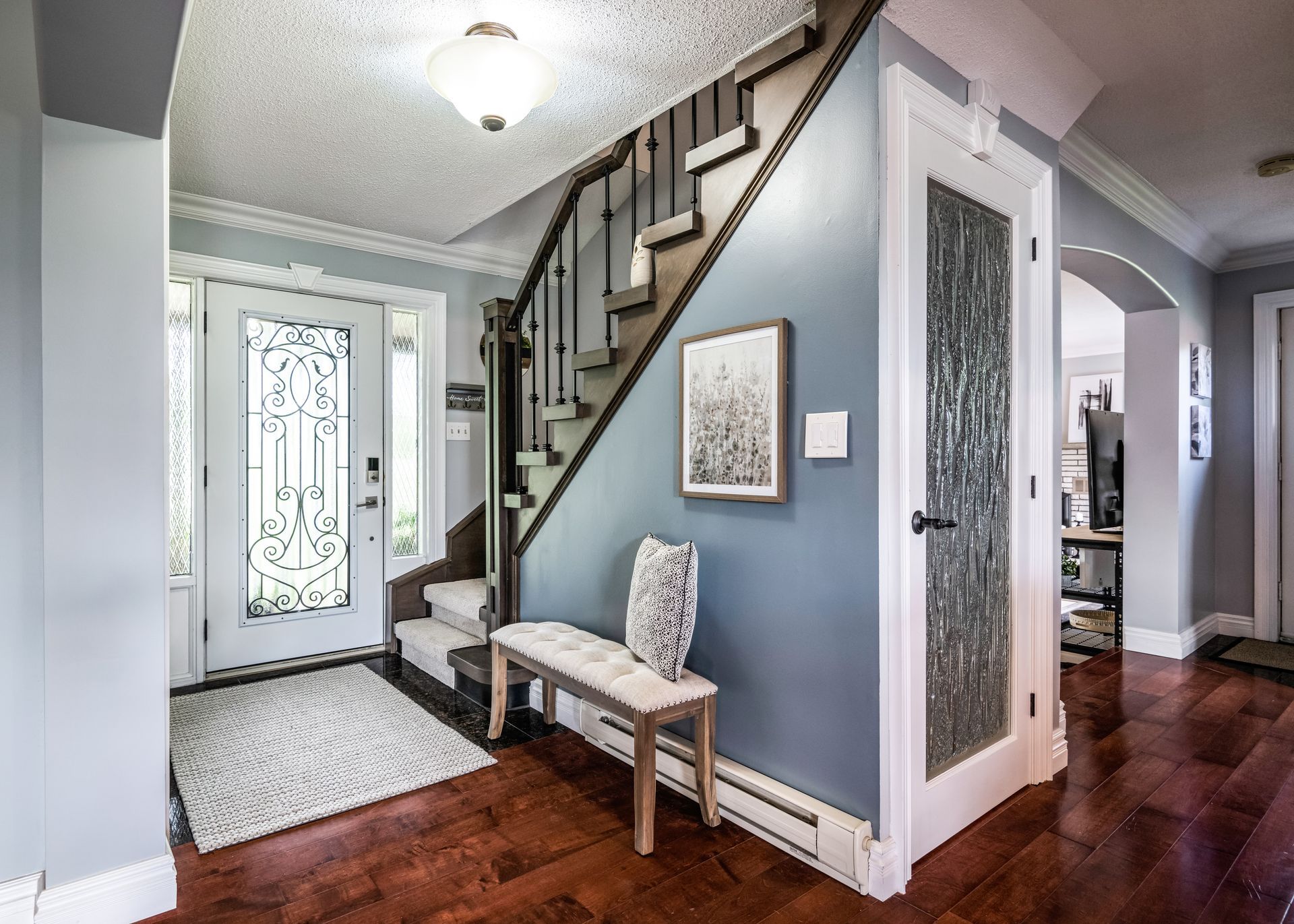 A hallway with a bench and stairs in a house.
