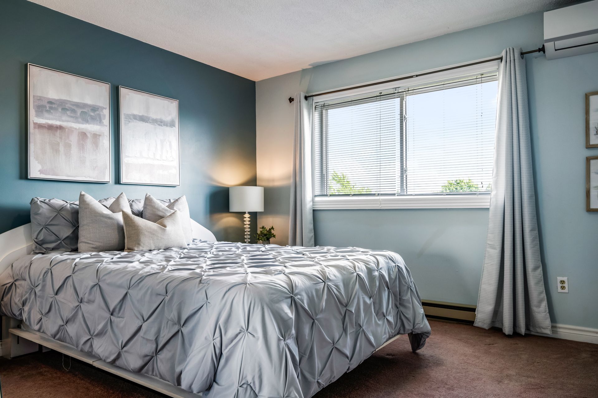 A bedroom with a large bed , blue walls and a window.