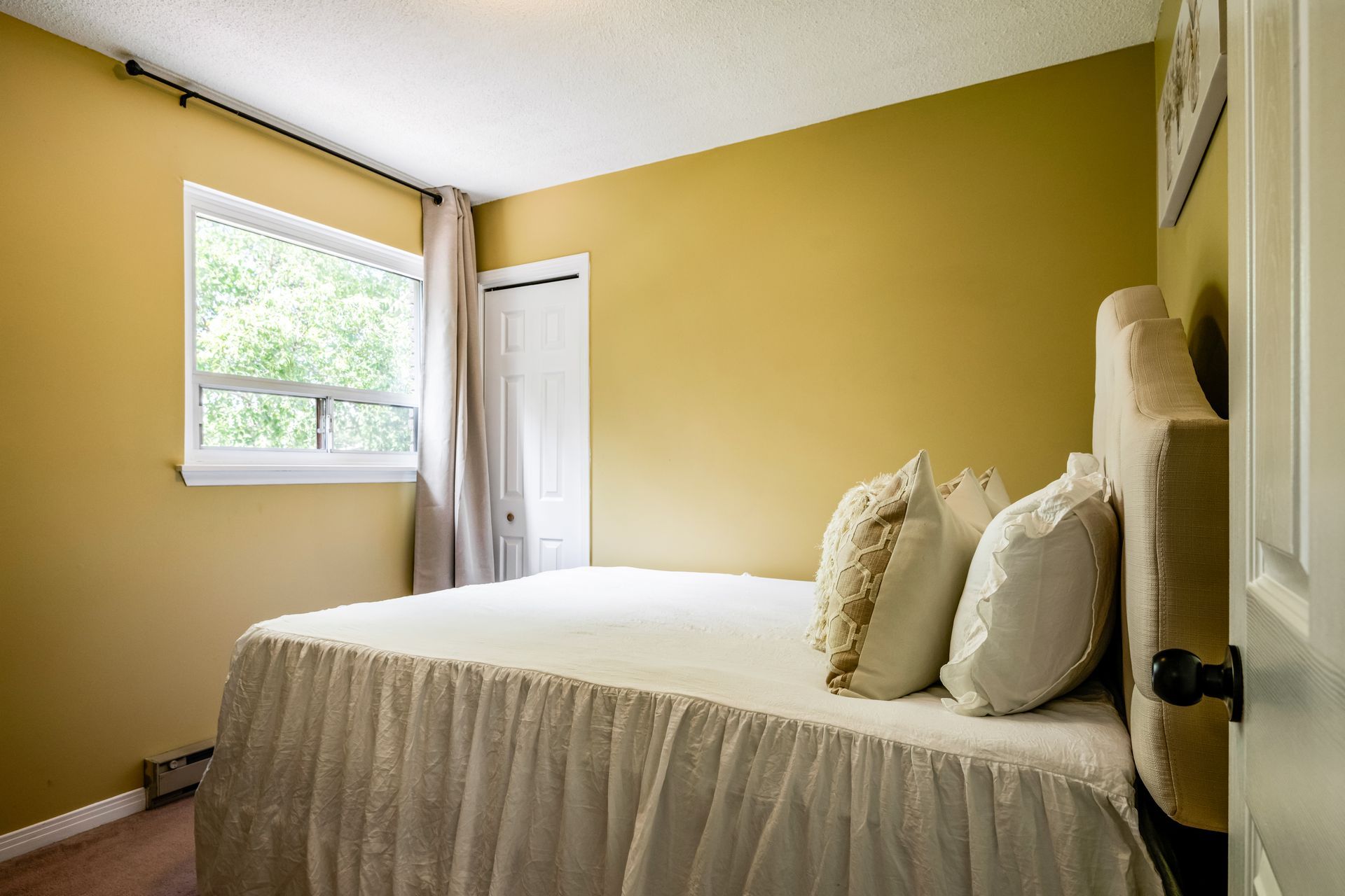 A bedroom with a bed , window and yellow walls.