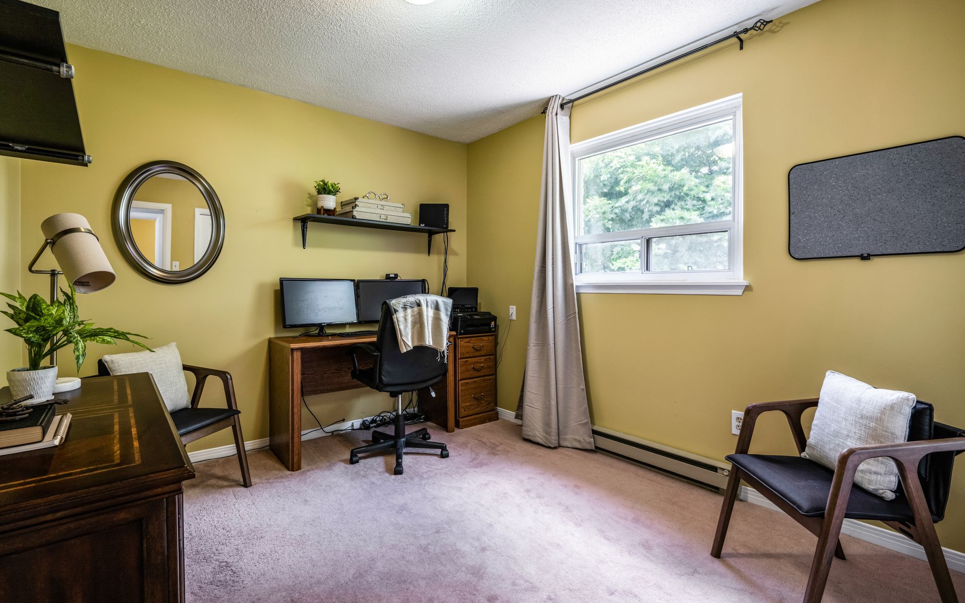A room with a desk , chairs , a computer and a window.