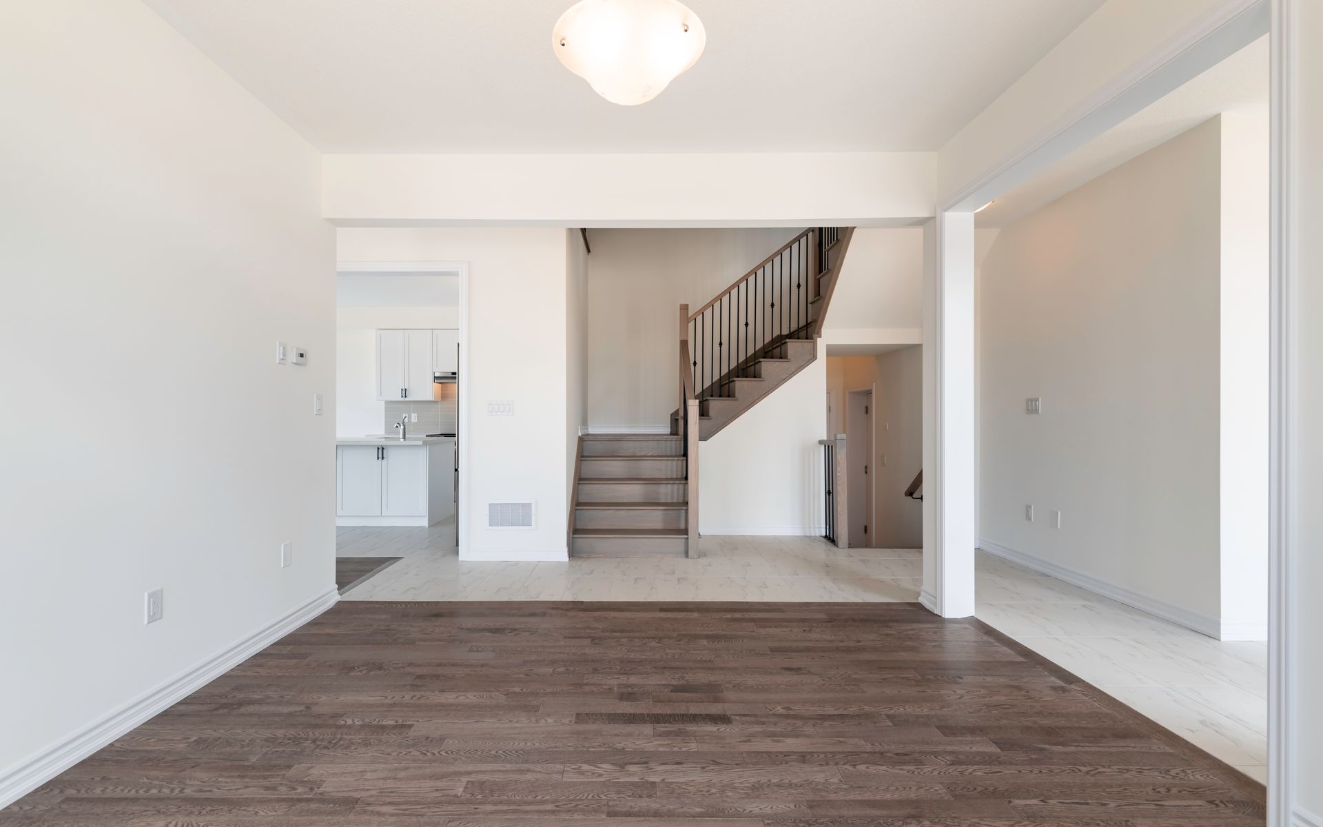 An empty living room with hardwood floors and stairs in a house.