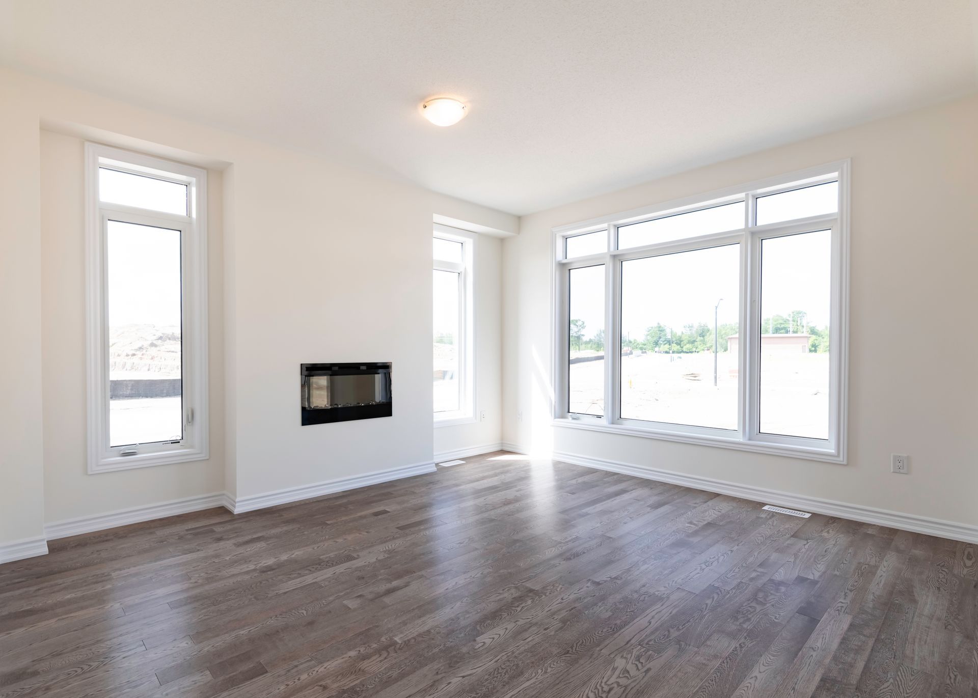 An empty living room with hardwood floors and a fireplace.