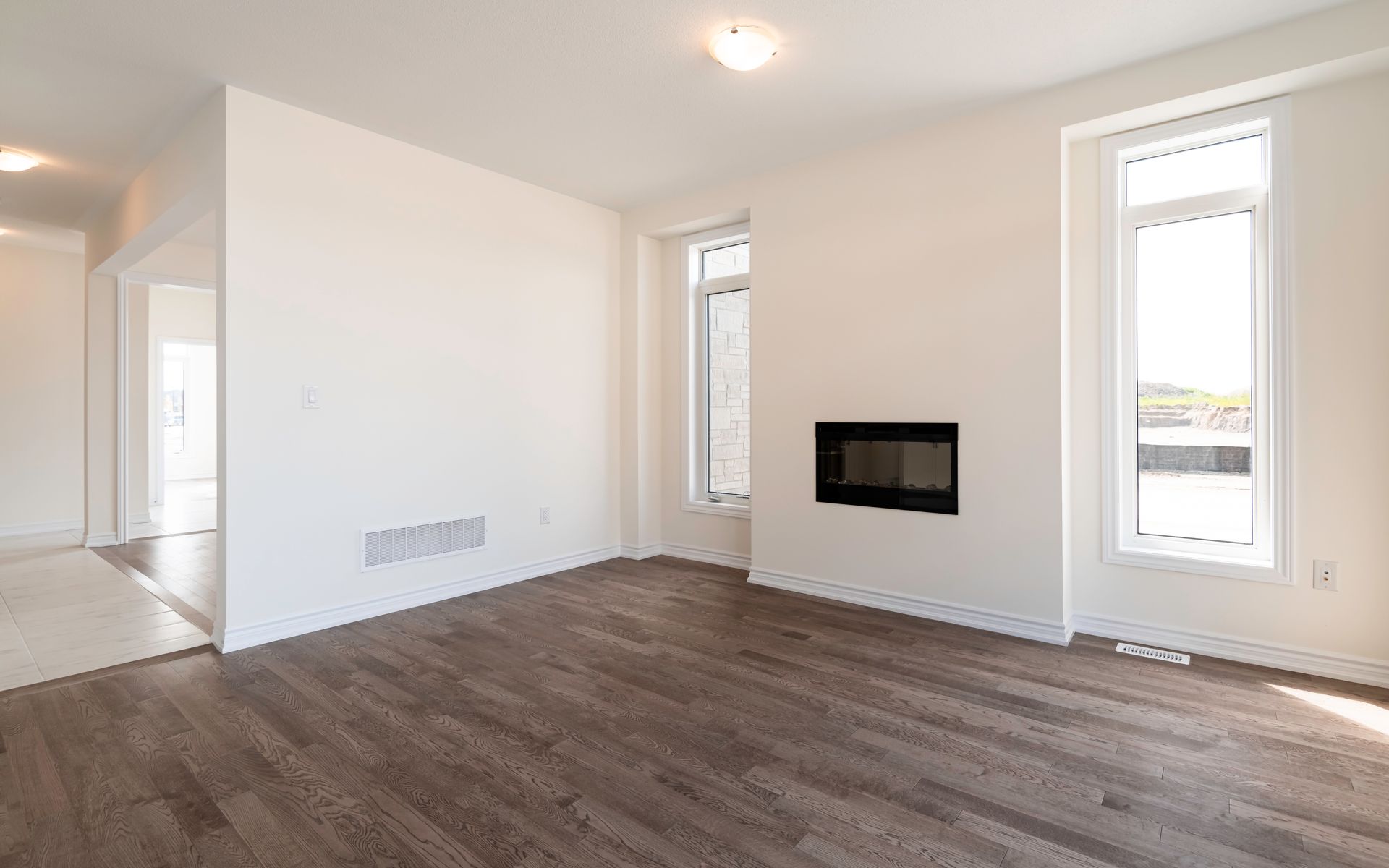 An empty living room with hardwood floors and a fireplace.