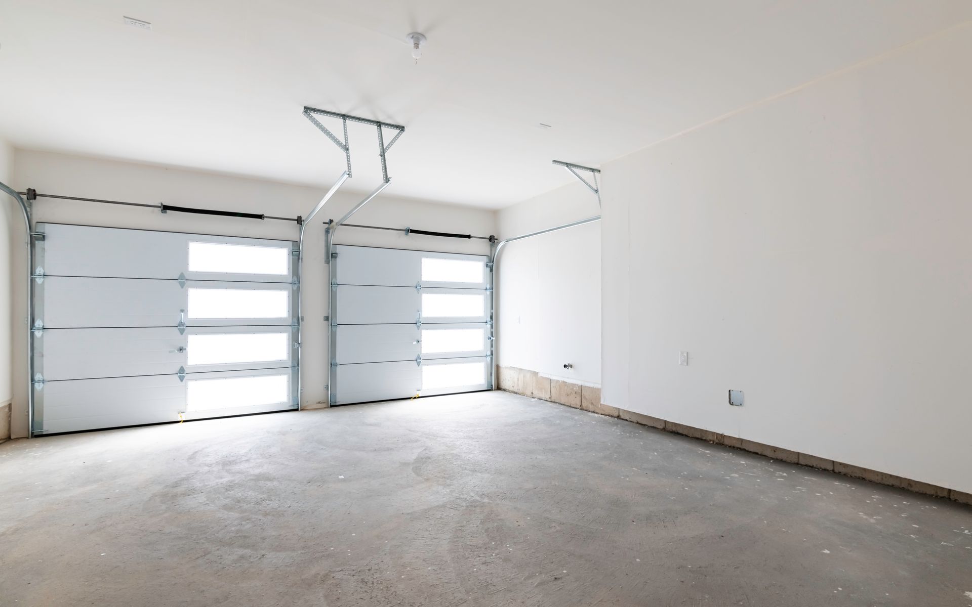 An empty garage with two garage doors open.