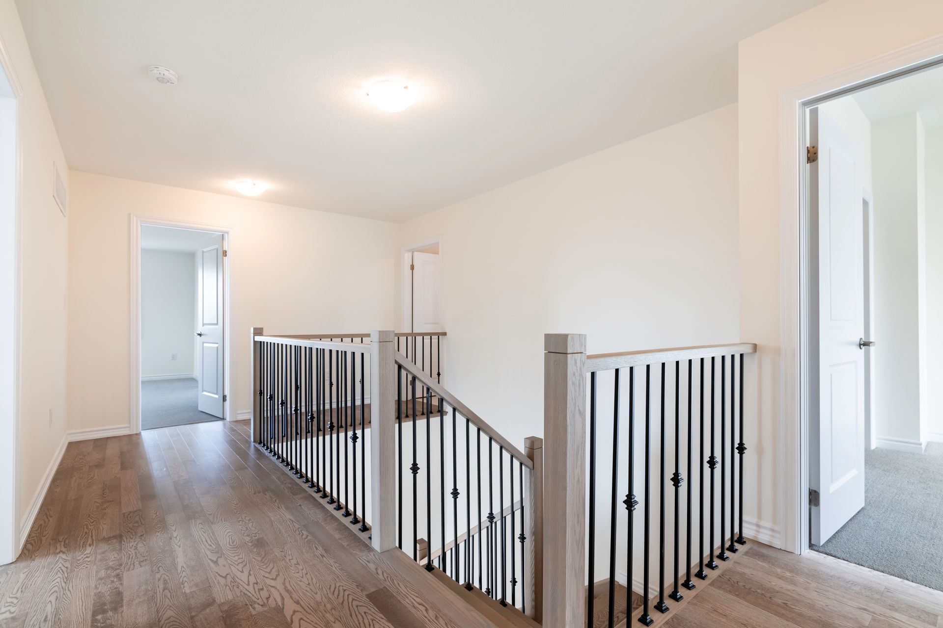 A hallway with a staircase and a railing in a house.
