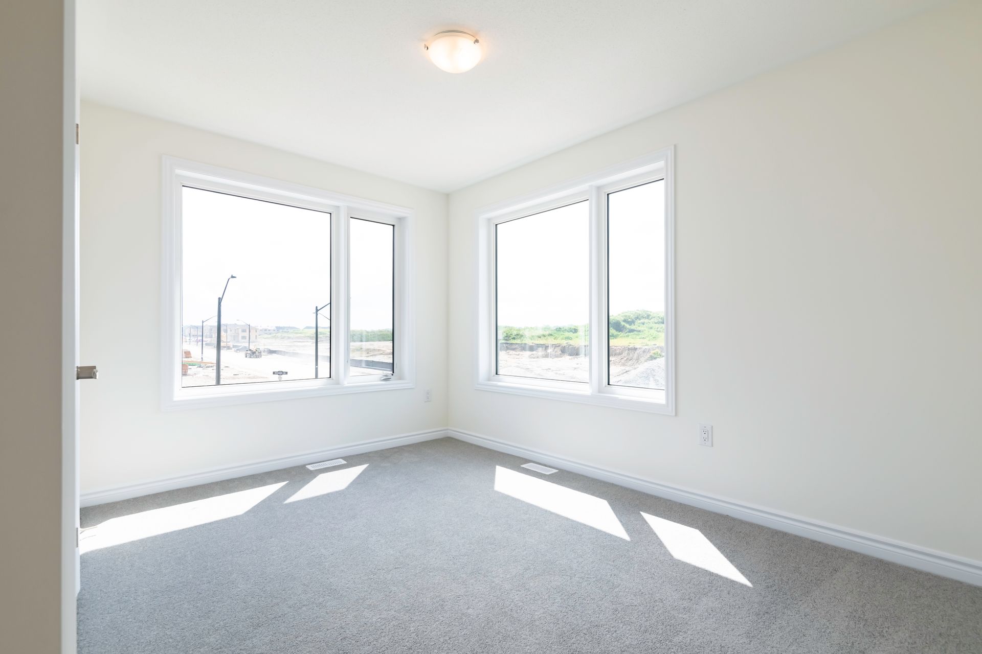 An empty bedroom with a lot of windows and a carpeted floor.