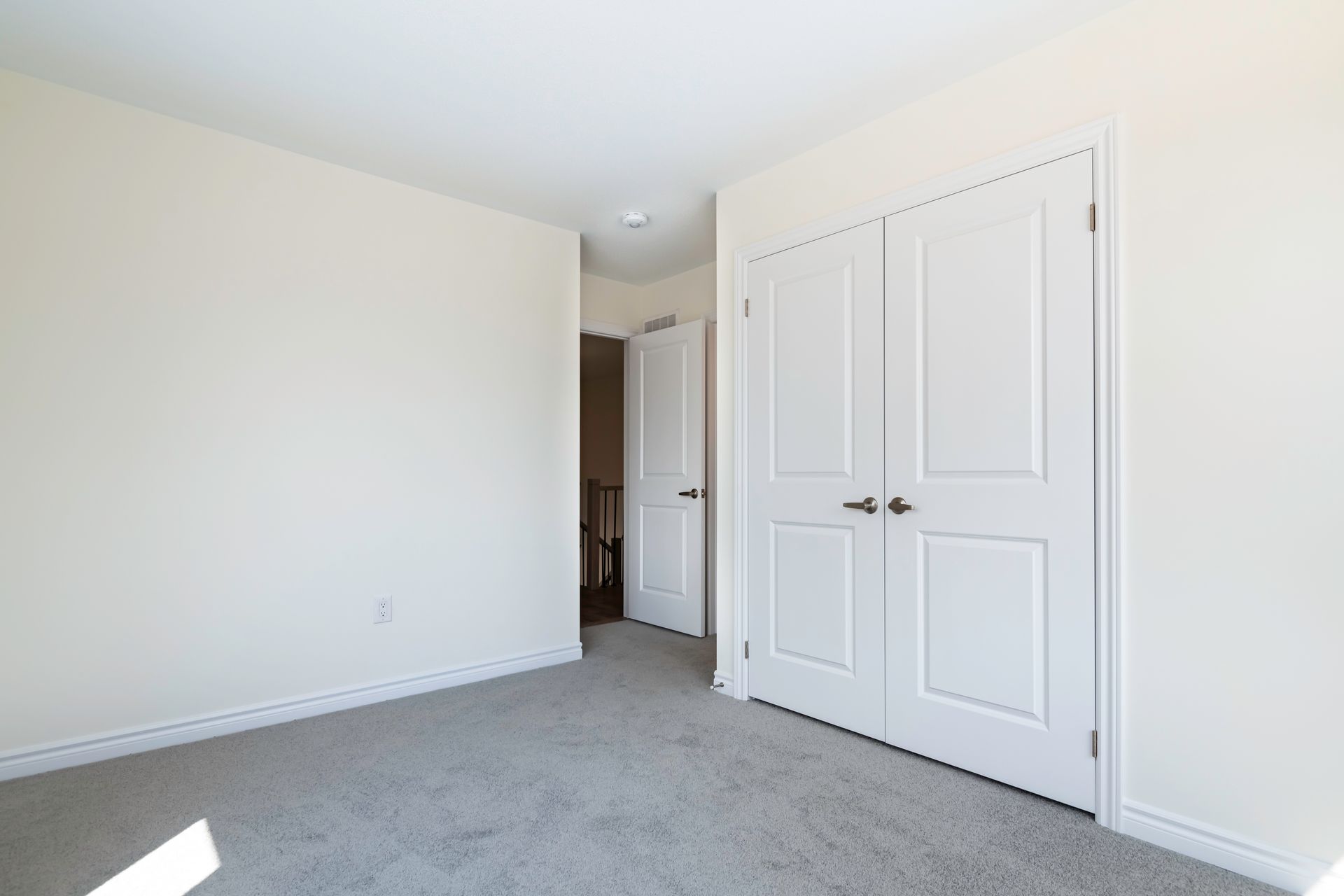 An empty bedroom with a carpeted floor and white walls.