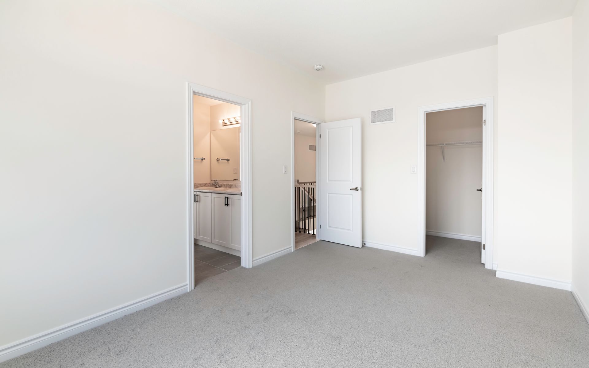 An empty bedroom with a bathroom and a closet.