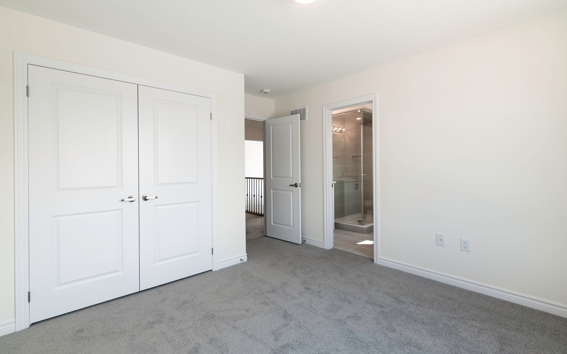 An empty bedroom with a gray carpet and white walls.