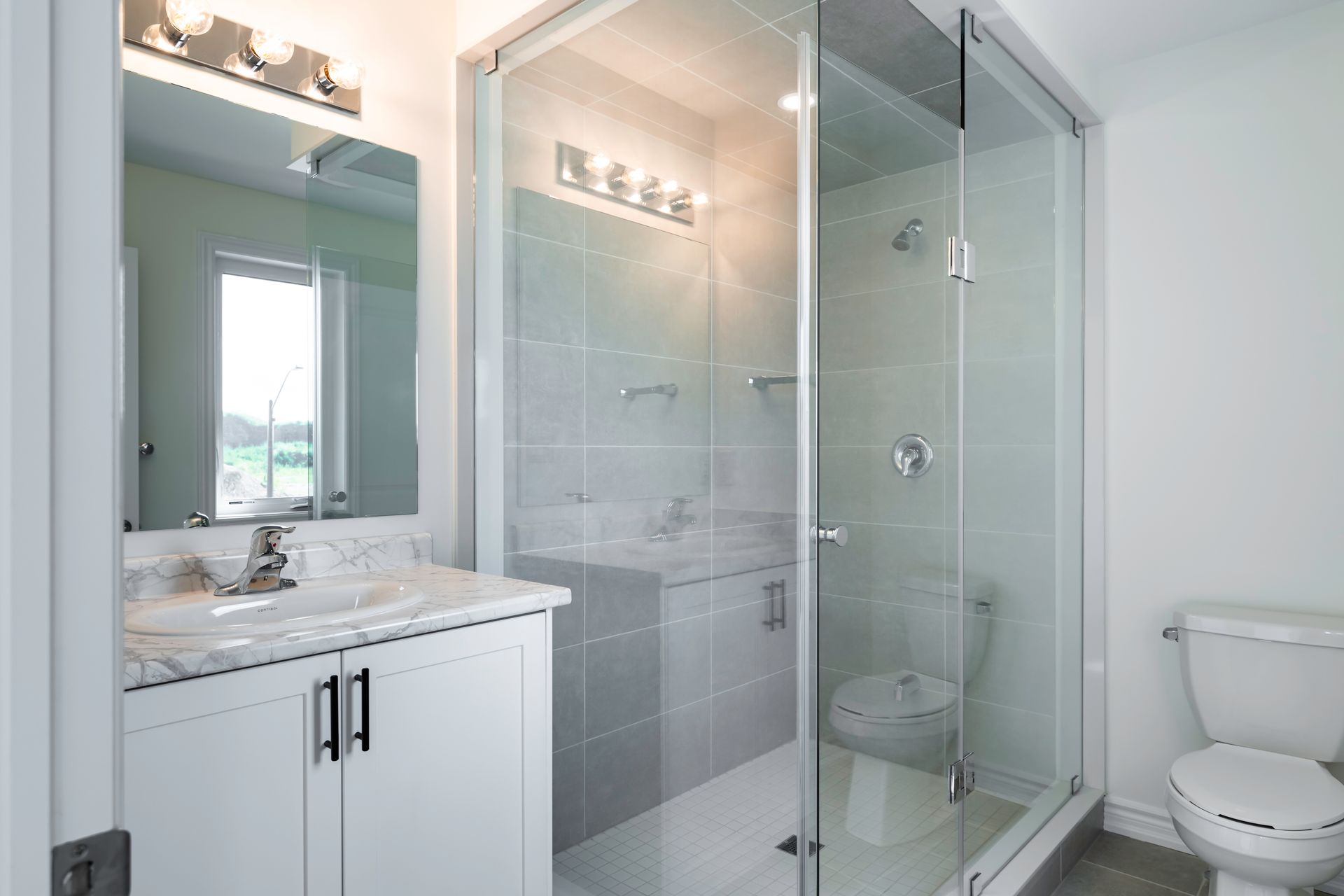 A bathroom with a toilet , sink , shower and mirror.