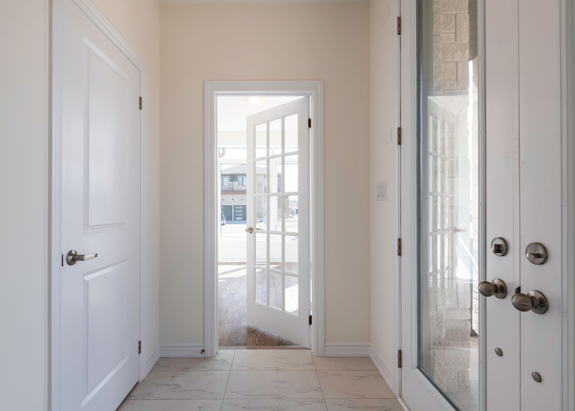 An empty hallway with white doors and a glass door.