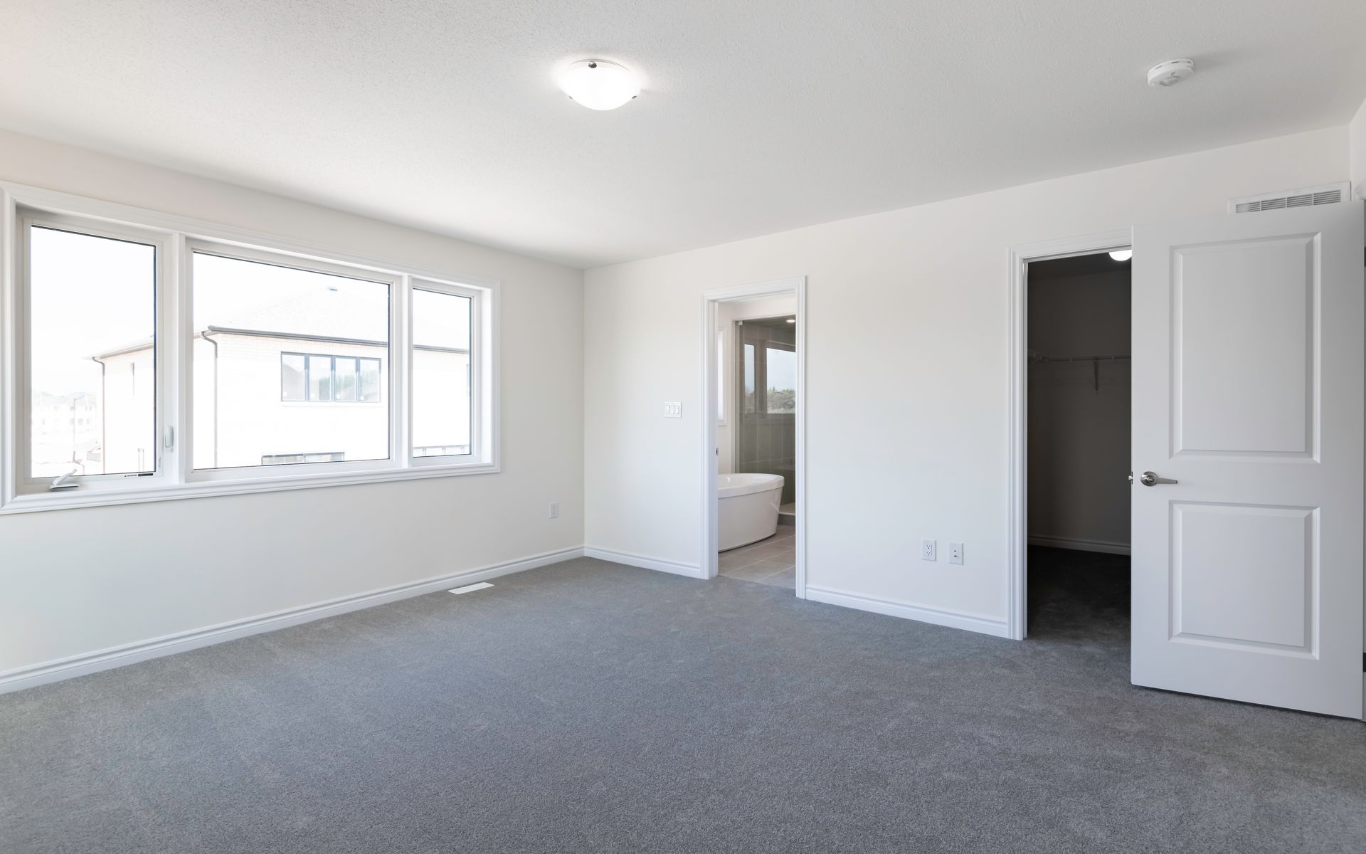 An empty bedroom with a gray carpet and white walls.