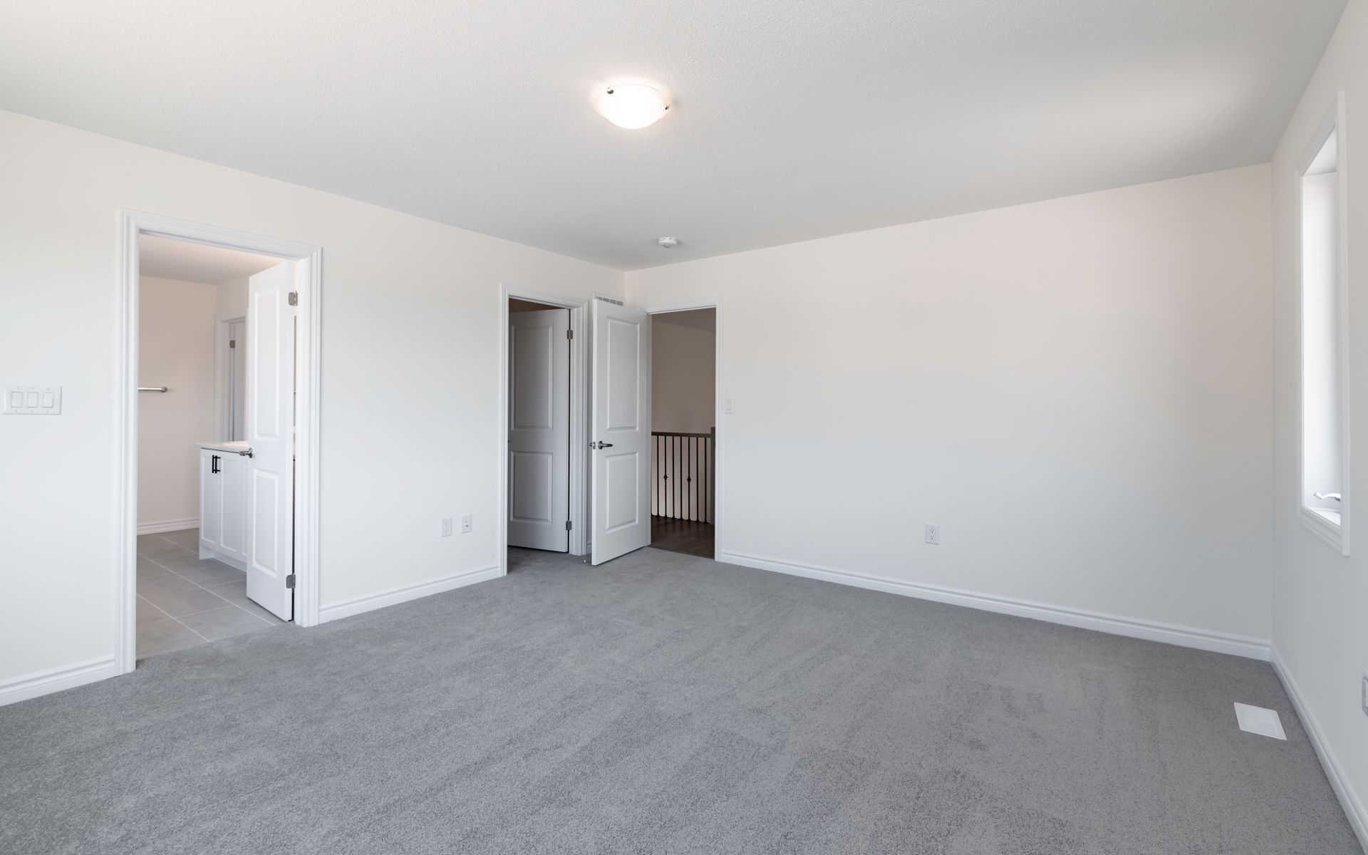 an empty bedroom with a gray carpet and white walls .