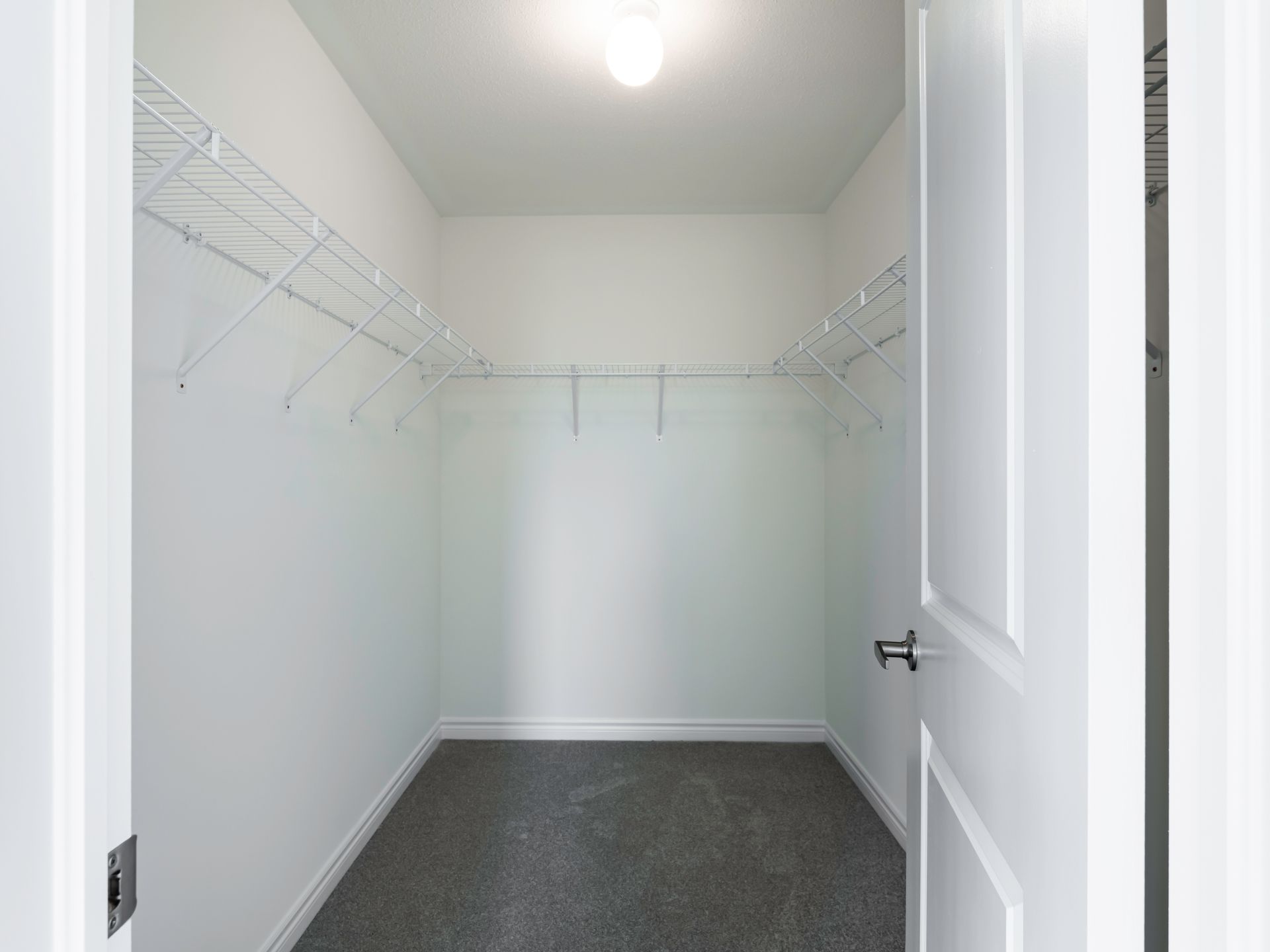 An empty walk in closet in a house with a door open.