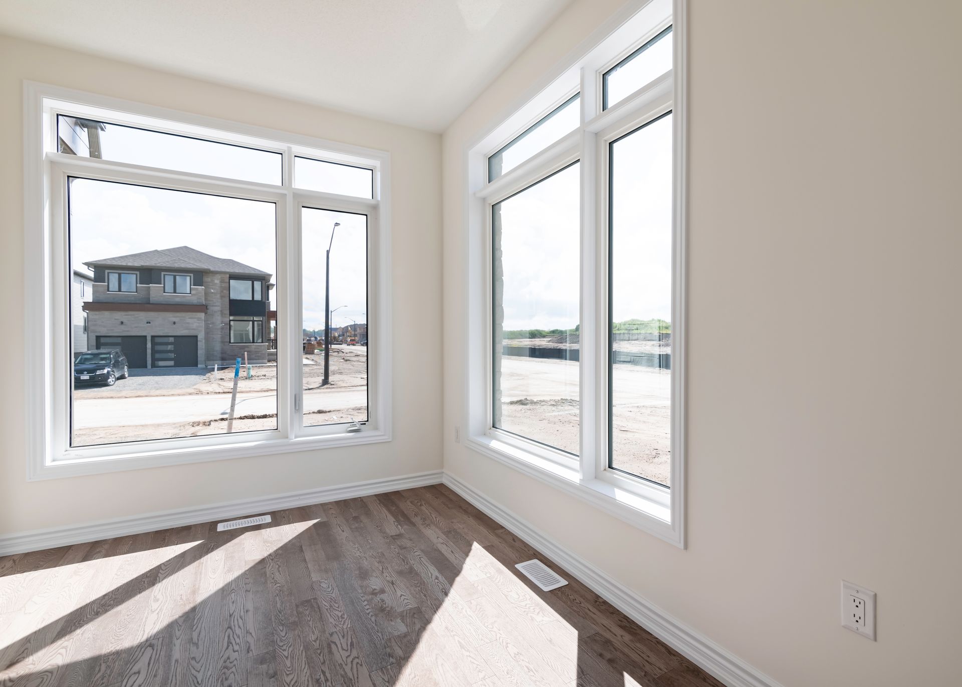 An empty room with a lot of windows and a house in the background.