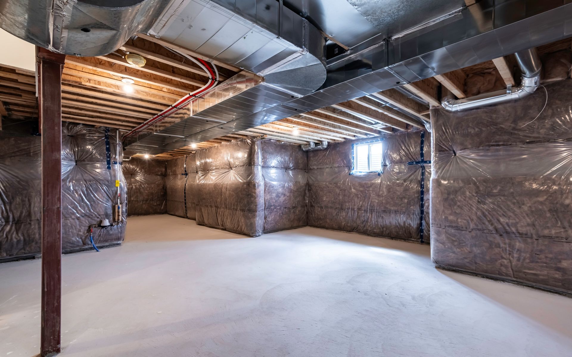 An empty basement with a ceiling fan and a window.