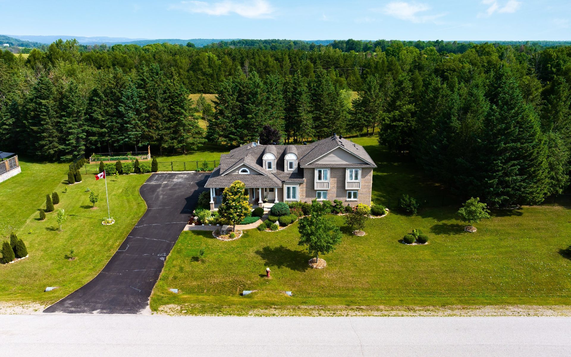 An aerial view of a large house surrounded by trees and grass.