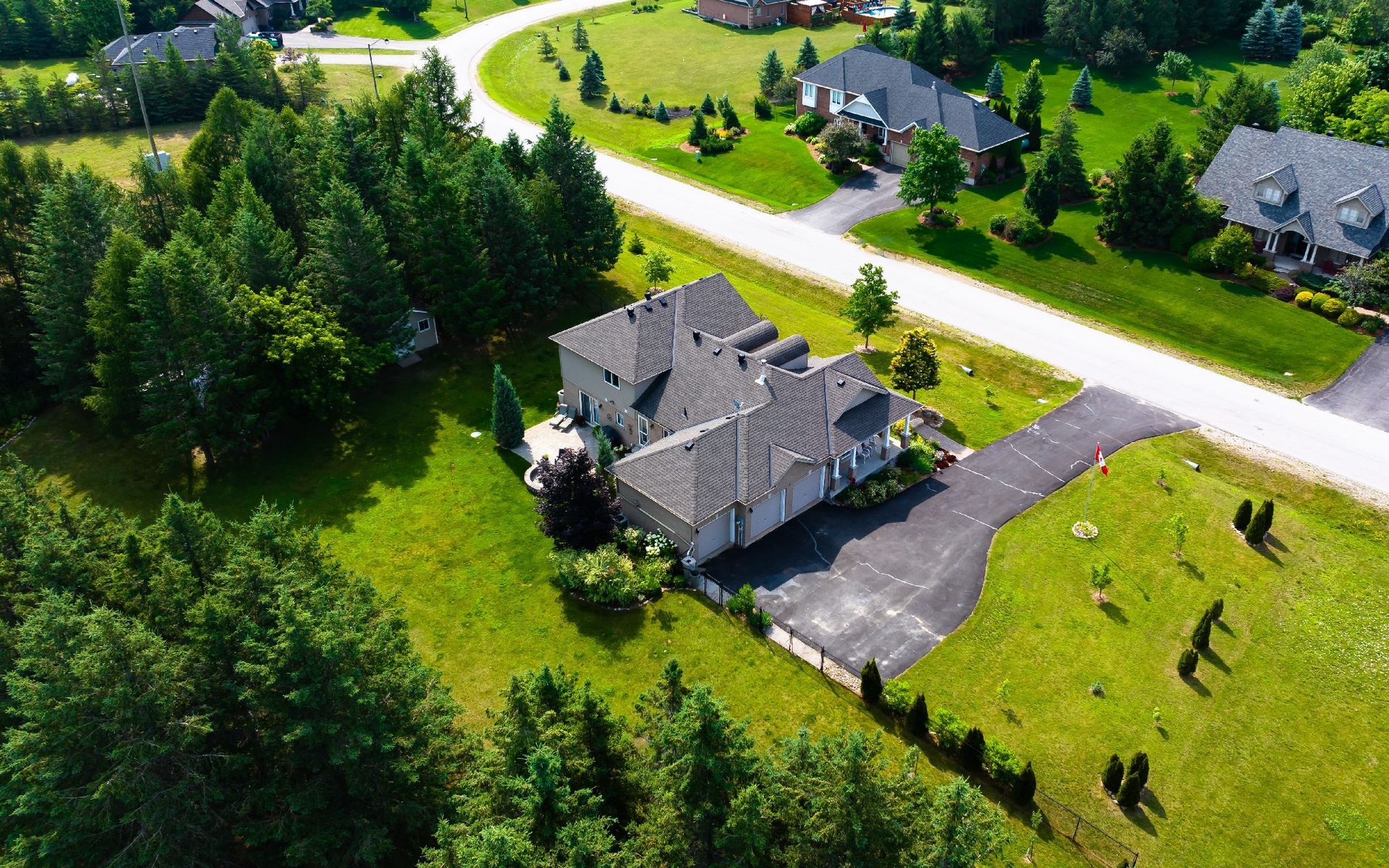 An aerial view of a house in a residential area surrounded by trees.