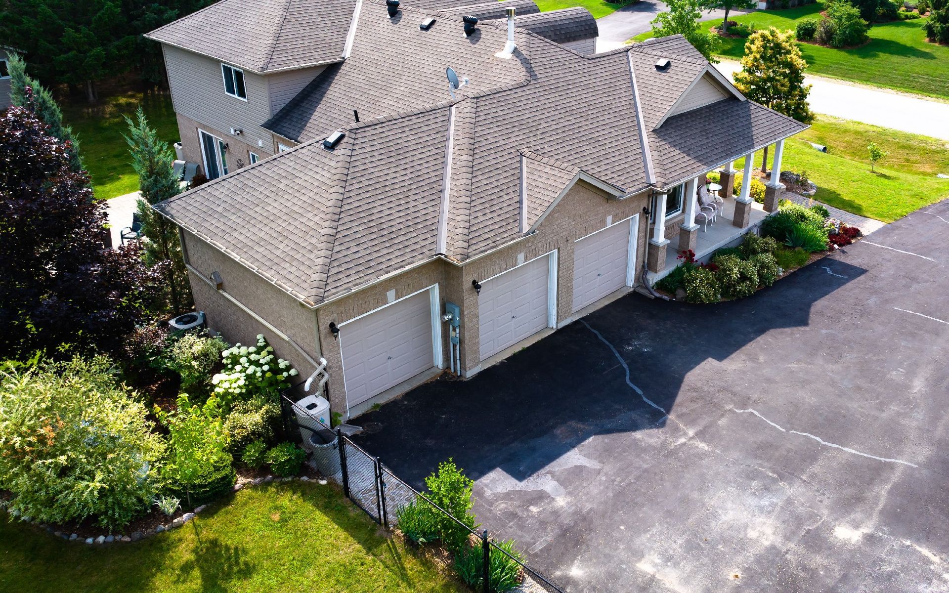 An aerial view of a large house with three garages and a driveway.
