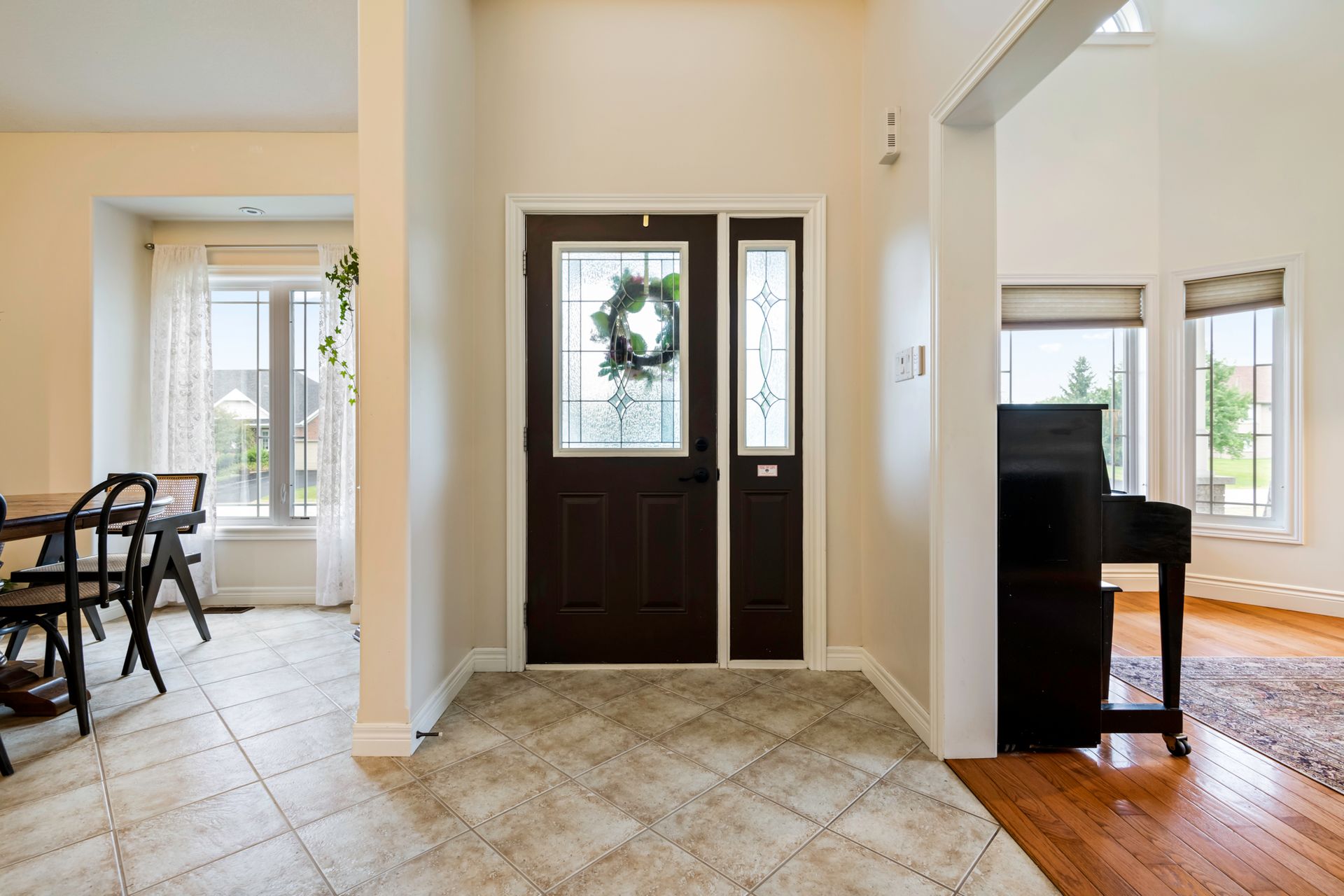 A hallway in a house with a piano and a wreath on the door.