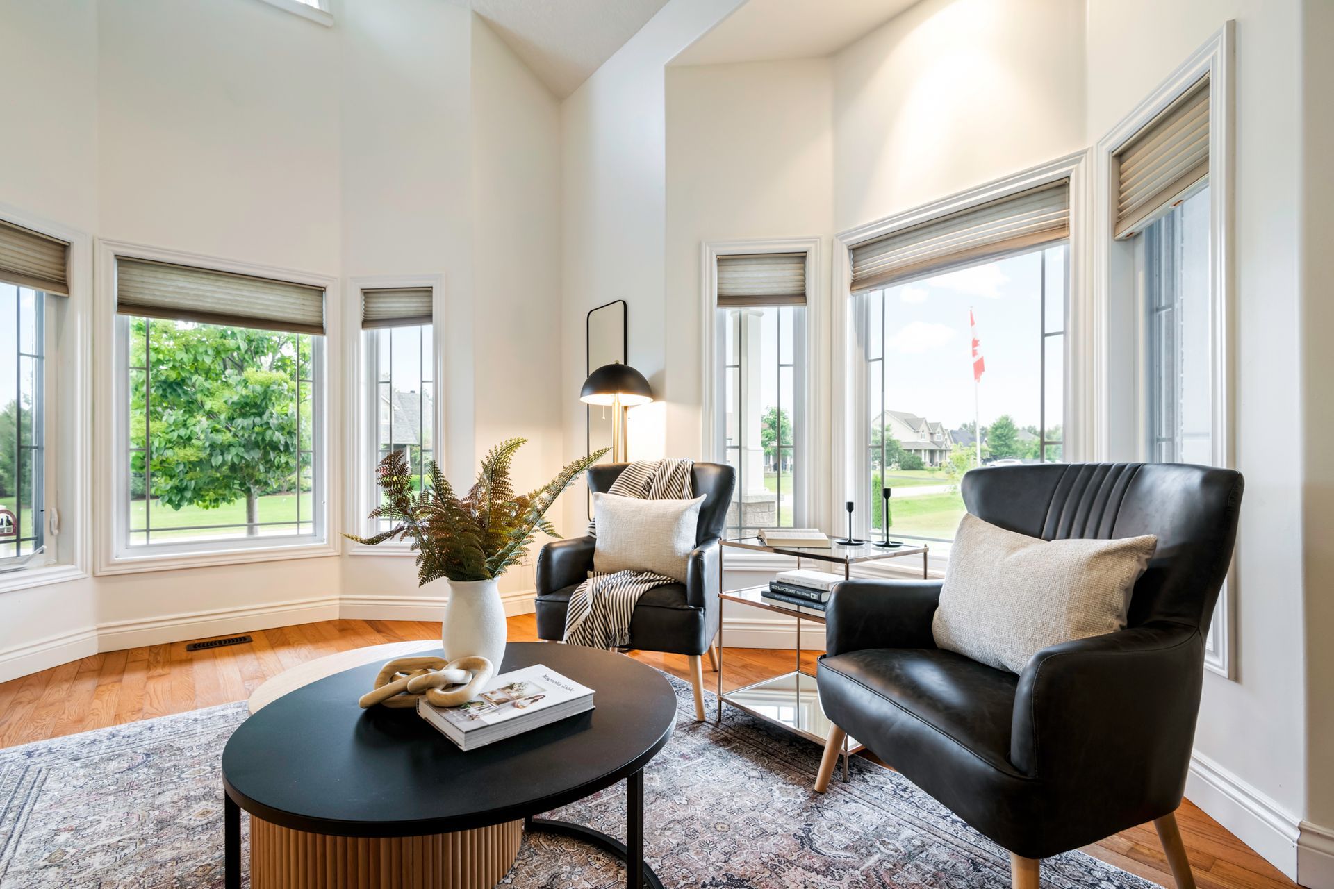 A living room with two chairs , a coffee table , and a large window.