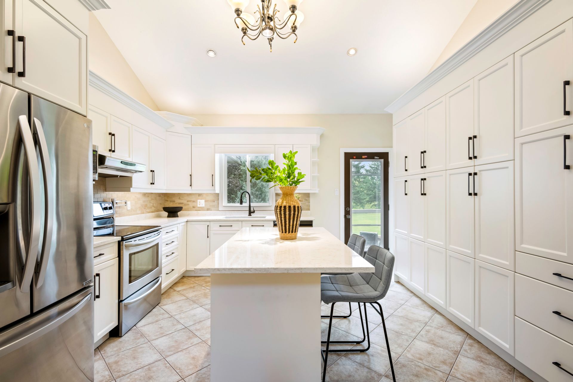 A kitchen with white cabinets , stainless steel appliances , and a large island.