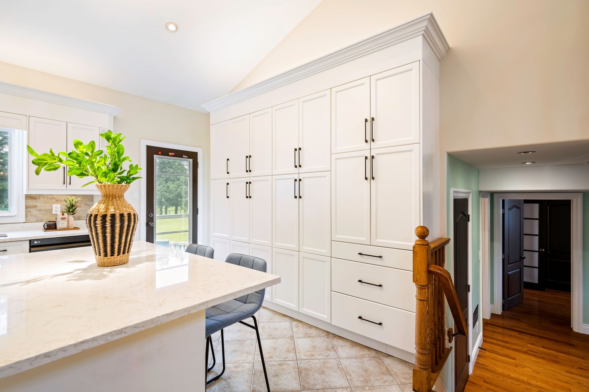 A kitchen with white cabinets and a vase on the counter.