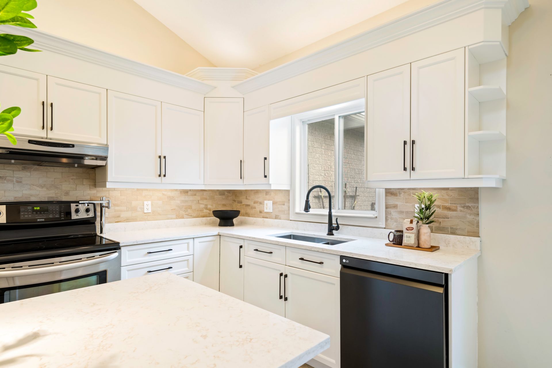 A kitchen with white cabinets , black appliances , a sink , and a window.