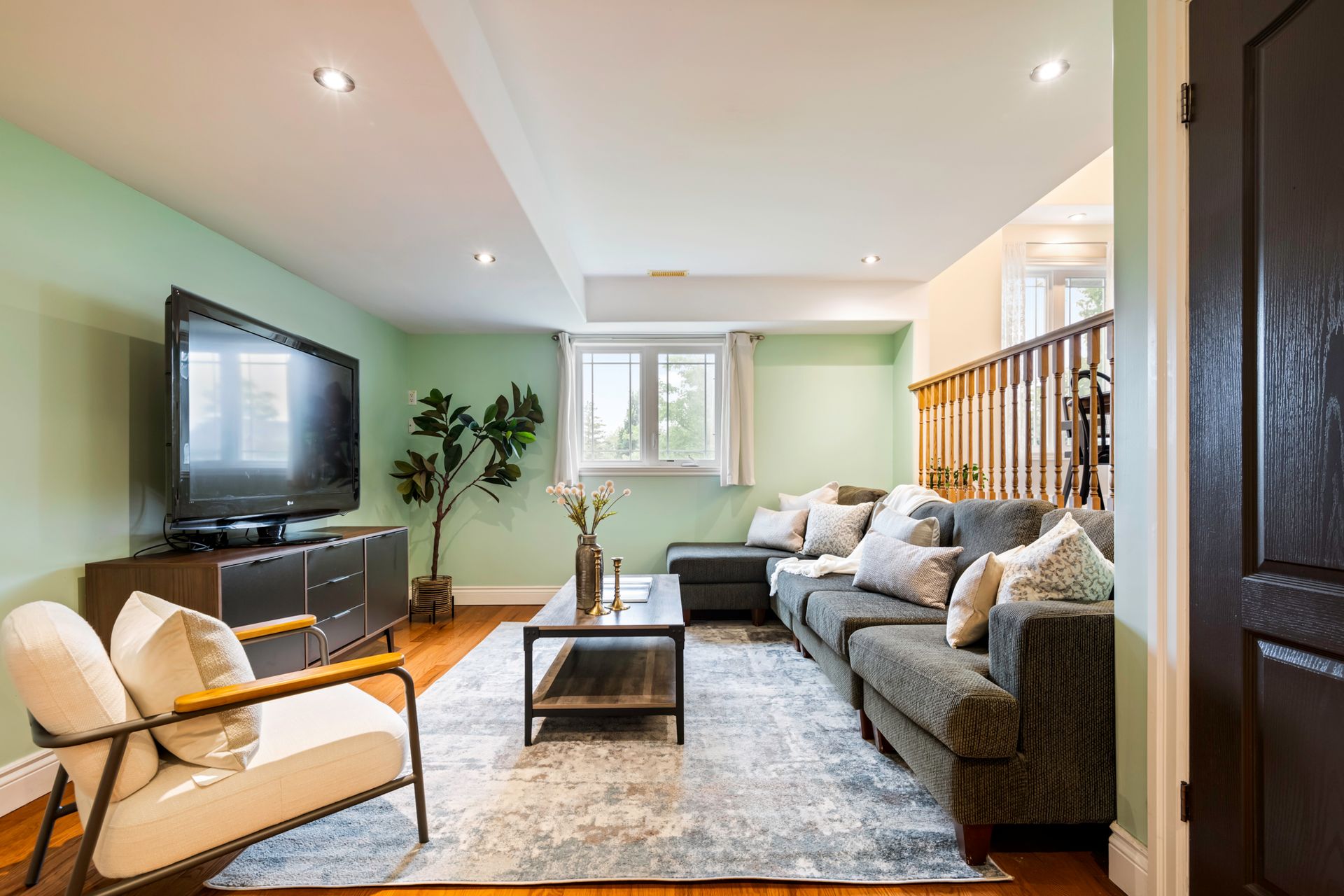 A living room with a couch , chair , coffee table and television.