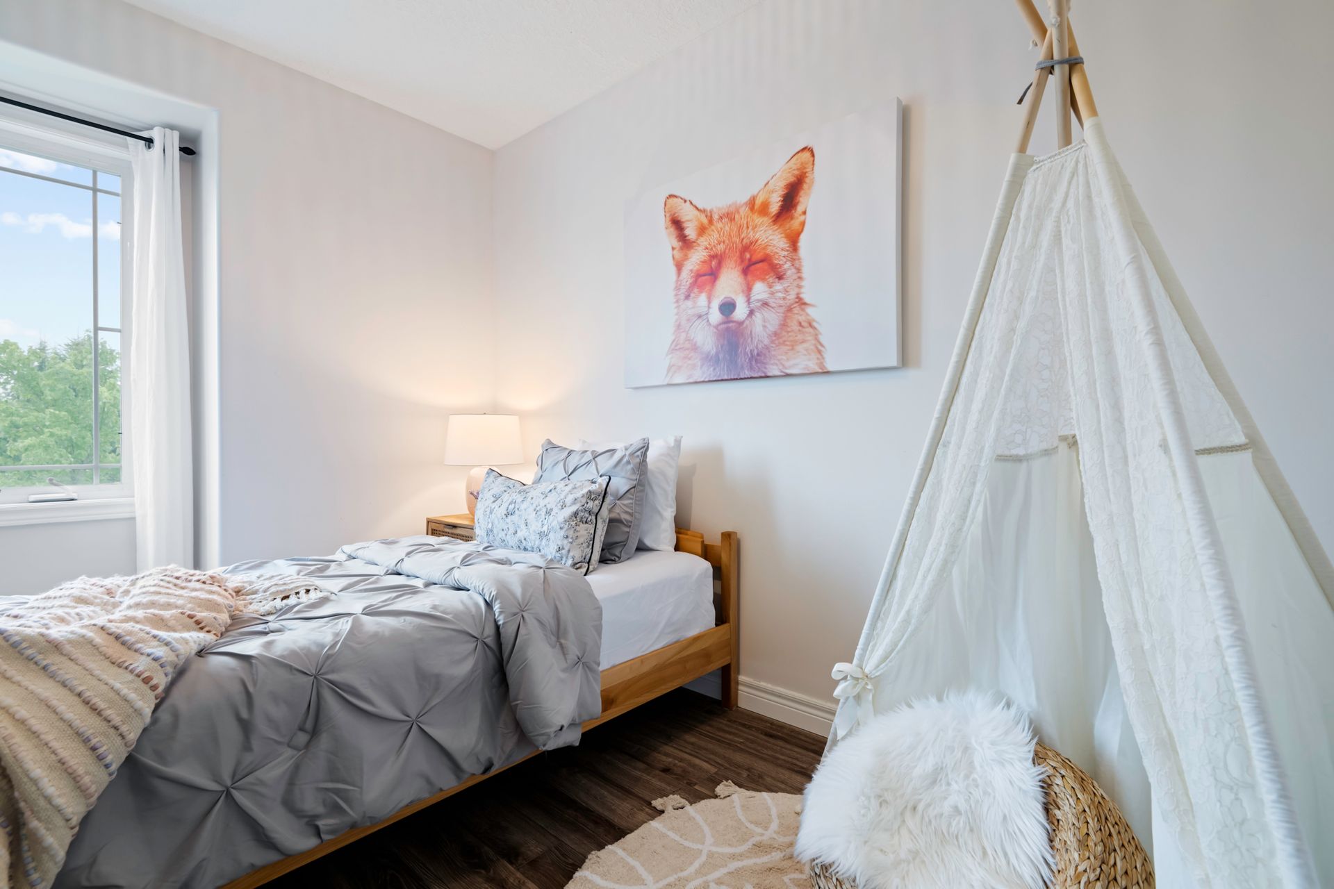 A bedroom with a bed , teepee and a painting of a fox on the wall.