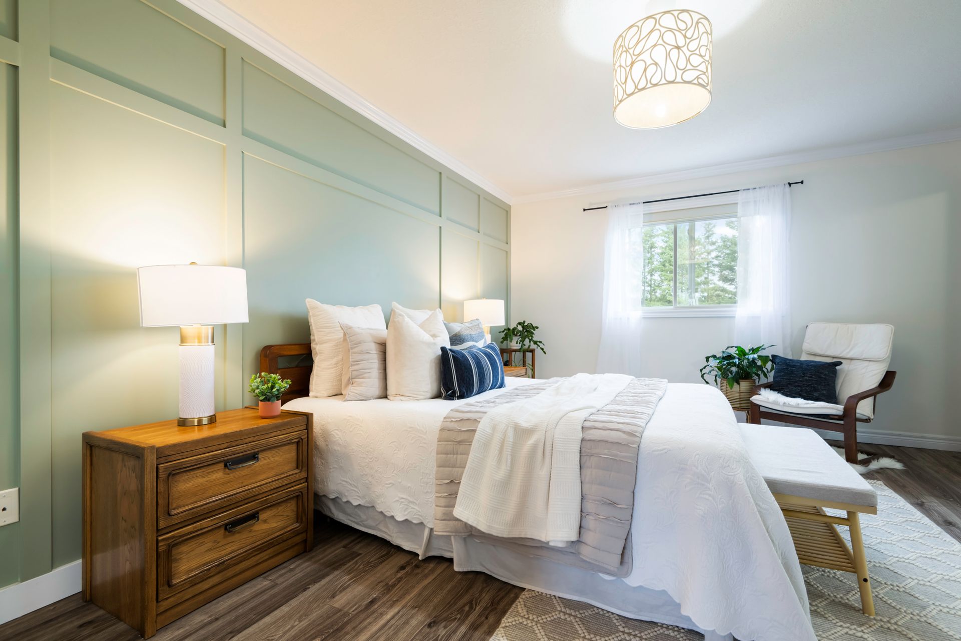 A bedroom with a bed , nightstand , chair and window.