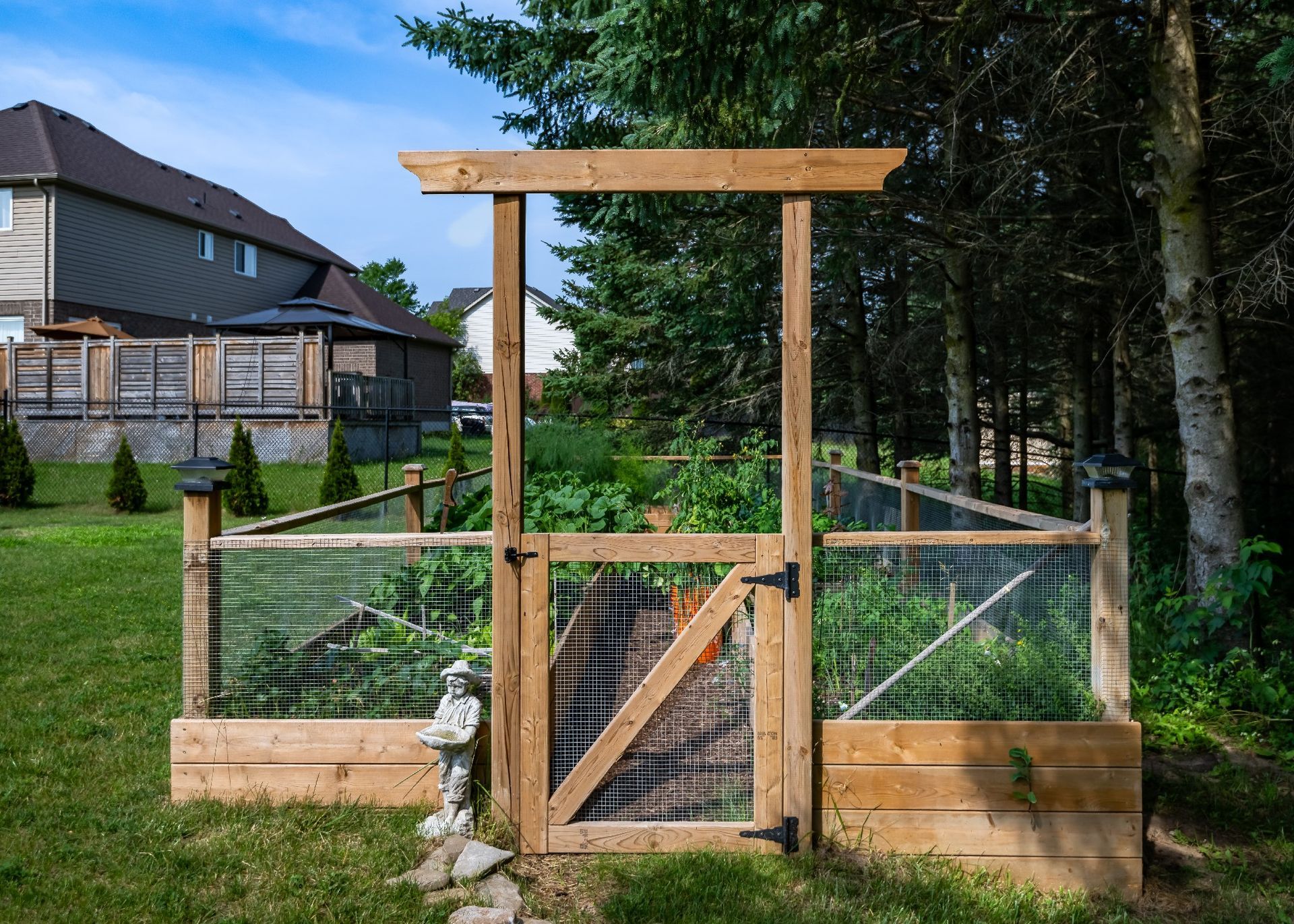 A wooden fence with a gate in the middle of a garden.