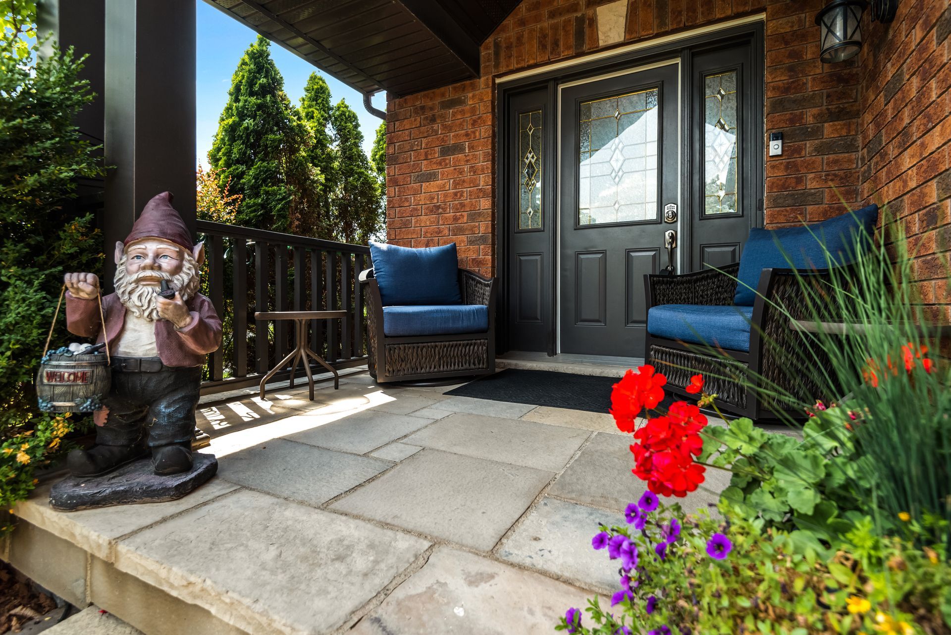 There is a gnome statue on the porch of a house.