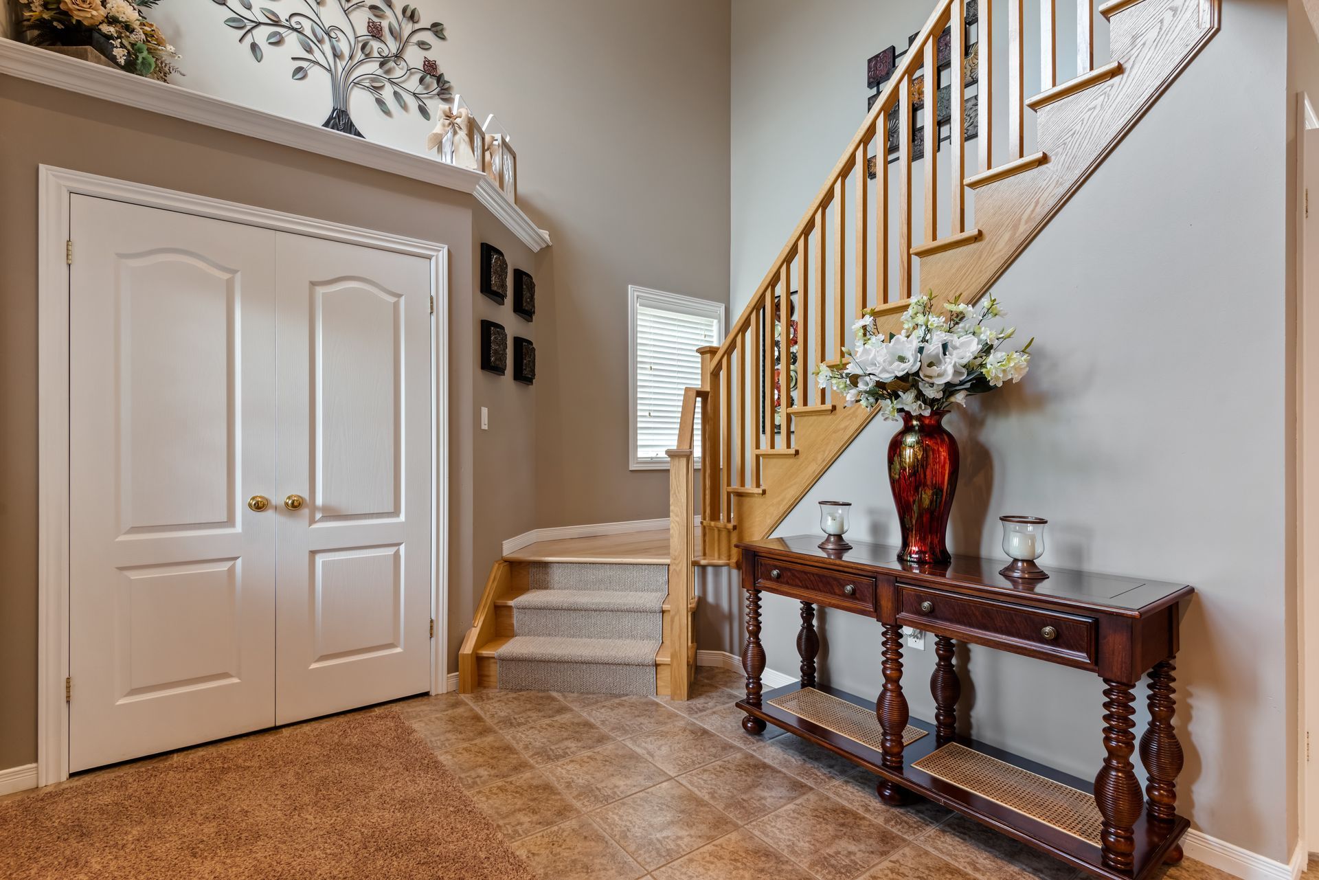 A hallway with stairs and a table with a vase of flowers on it.