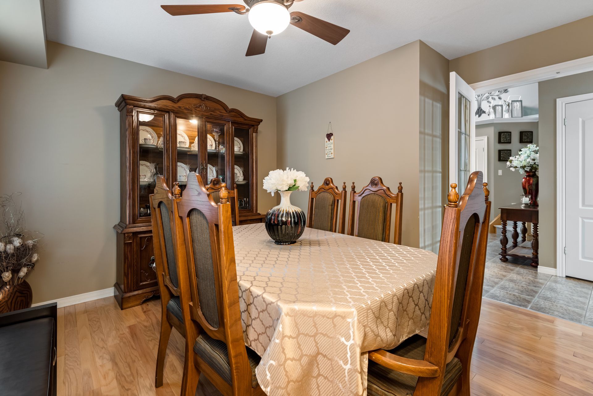 A dining room with a table and chairs and a ceiling fan.