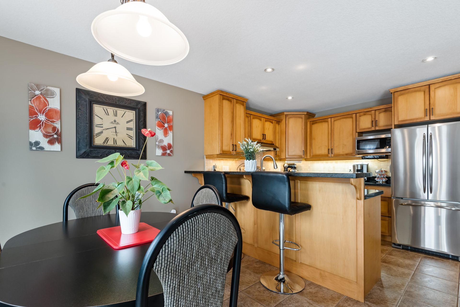 A kitchen with a table and chairs and a clock on the wall.