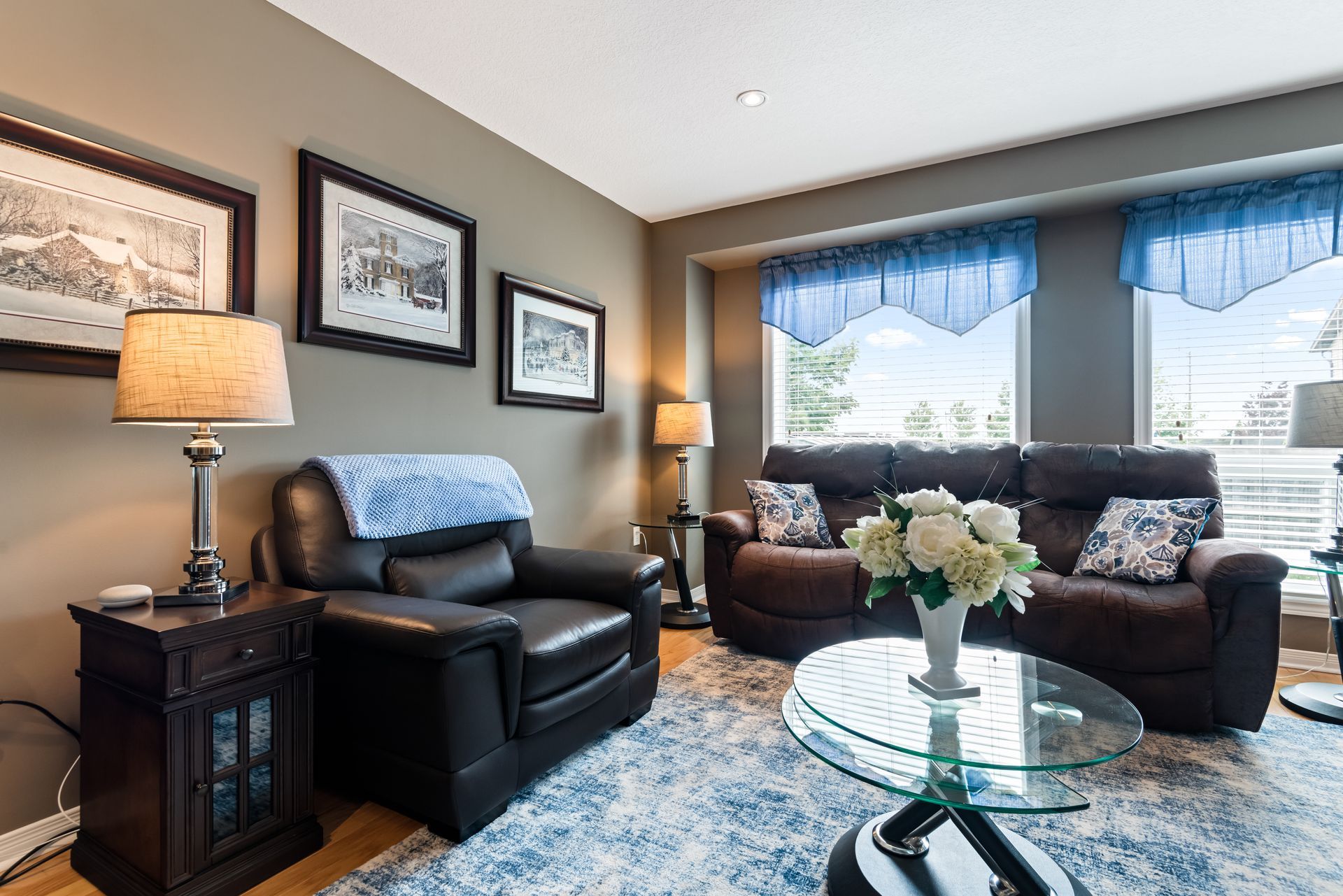 A living room with a couch , chair , coffee table and lamps.