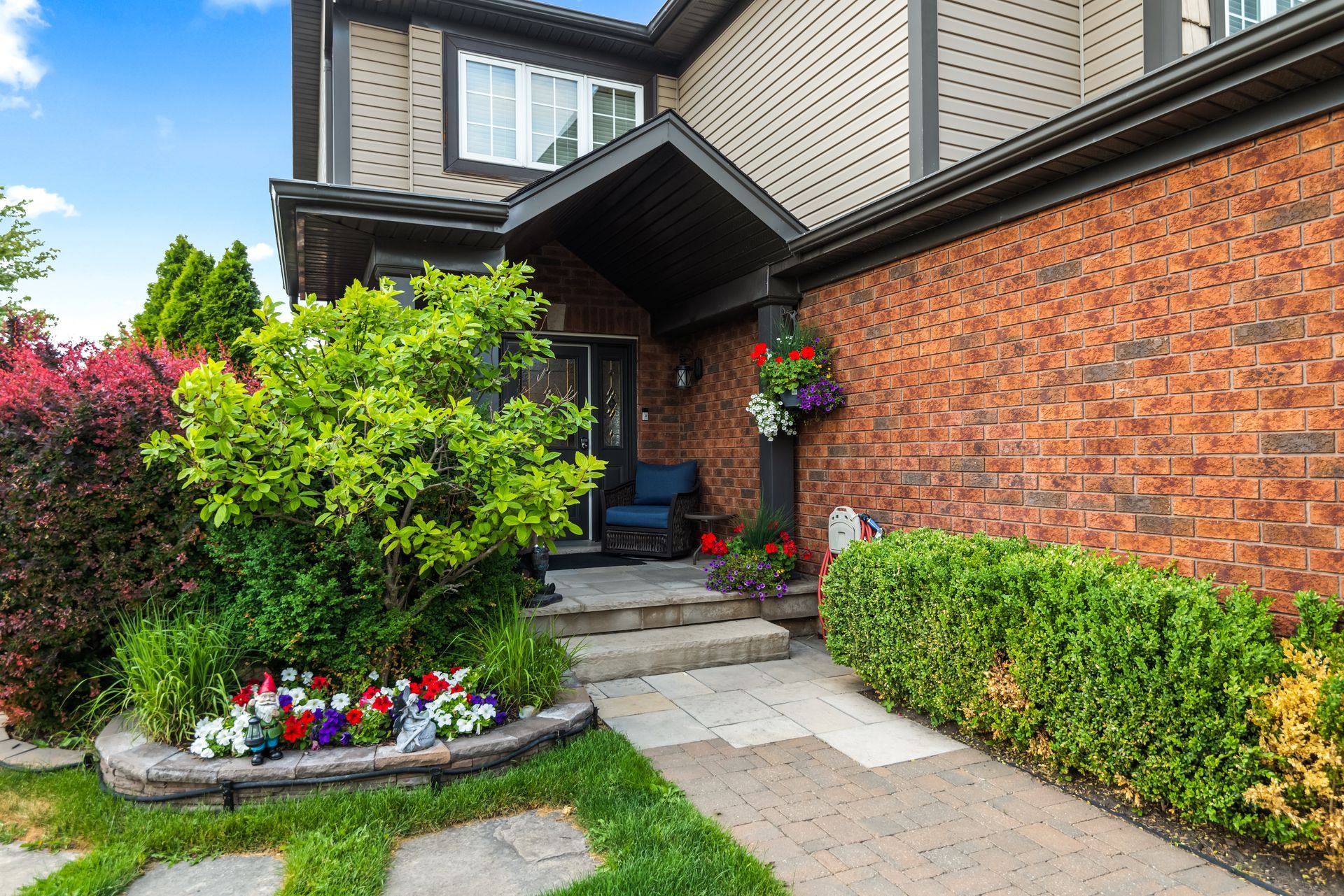 A brick house with a lush green garden in front of it.