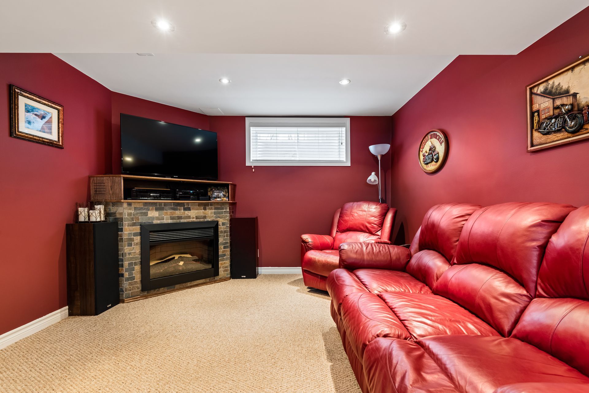 A living room with red walls , a red couch , a fireplace and a flat screen tv.